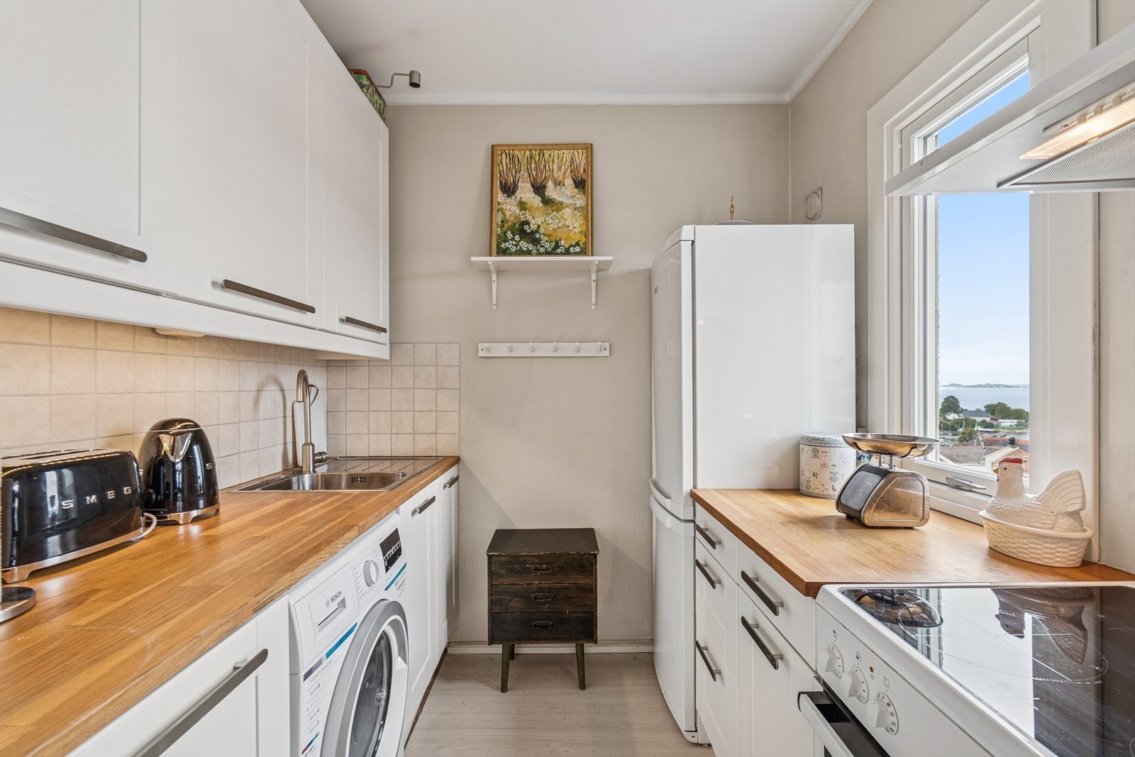 Kjøkkenet er godt utnyttet med god skap- og benkeplass. Frittstående hvitevarer og opplegg til vaskemaskin. Galleribilde