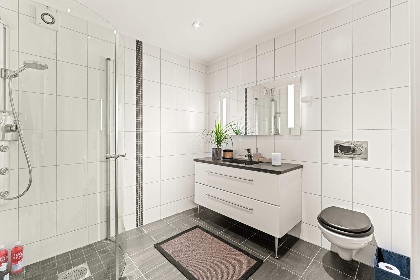 Flislagt bad med varmekabler, dusjhjørne med innfellbare dører og servant med underskuffer Galleribilde