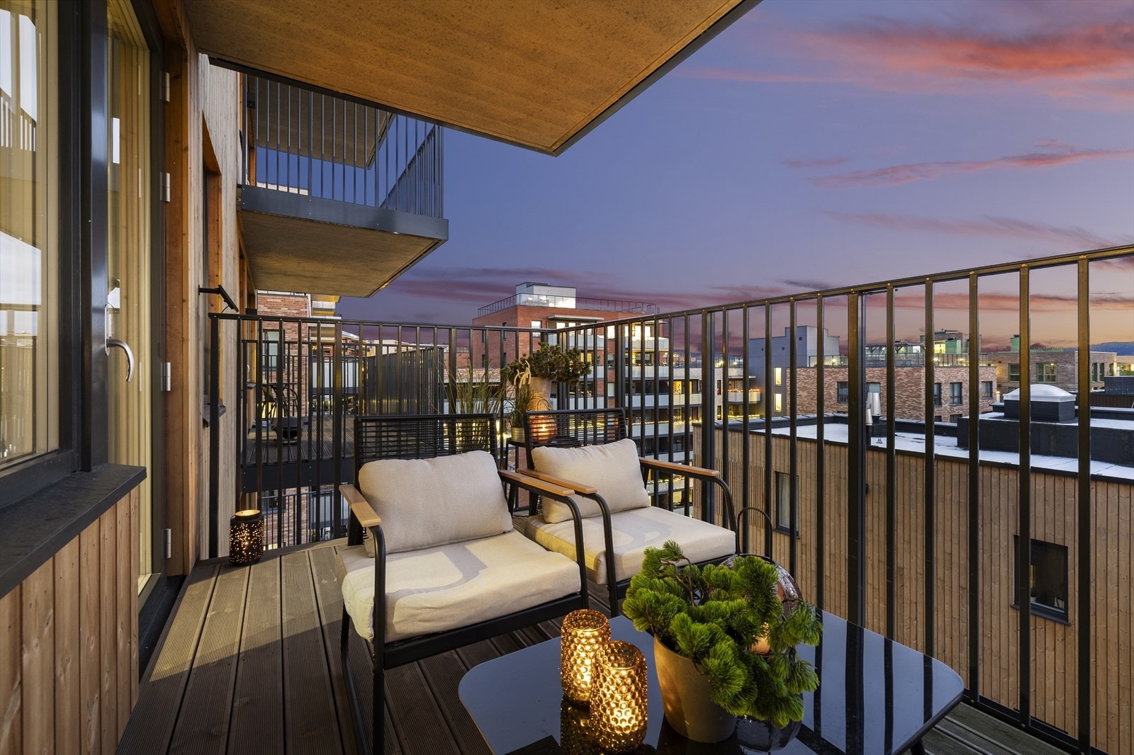 Balkongen er pent integrert i fasaden med en kombinasjon av trepanel og stålrekkverk. Galleribilde