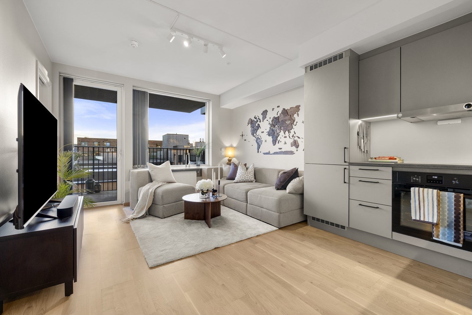 Store vindusflater og glassdør mot balkongen gir rikelig med naturlig lys til stue og kjøkken. Galleribilde