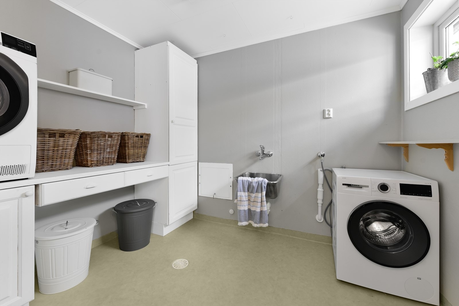 Praktisk og romslig vaskerom med god benkeplass og opplegg for vaskemaskin og tørketrommel. Galleribilde