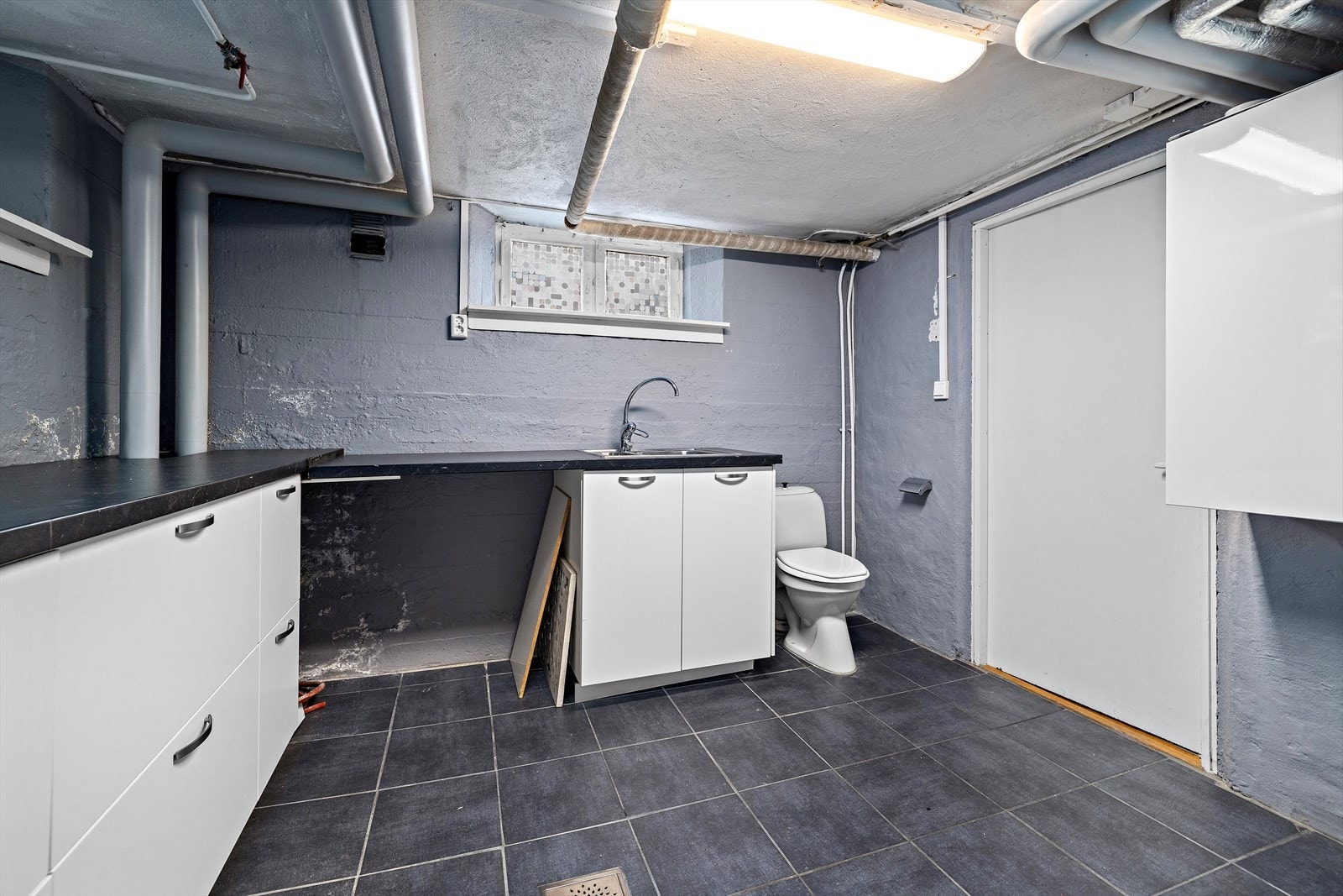 Praktisk vaskerom med benkeplass, utslagsvask og opplegg for vaskemaskin. Galleribilde