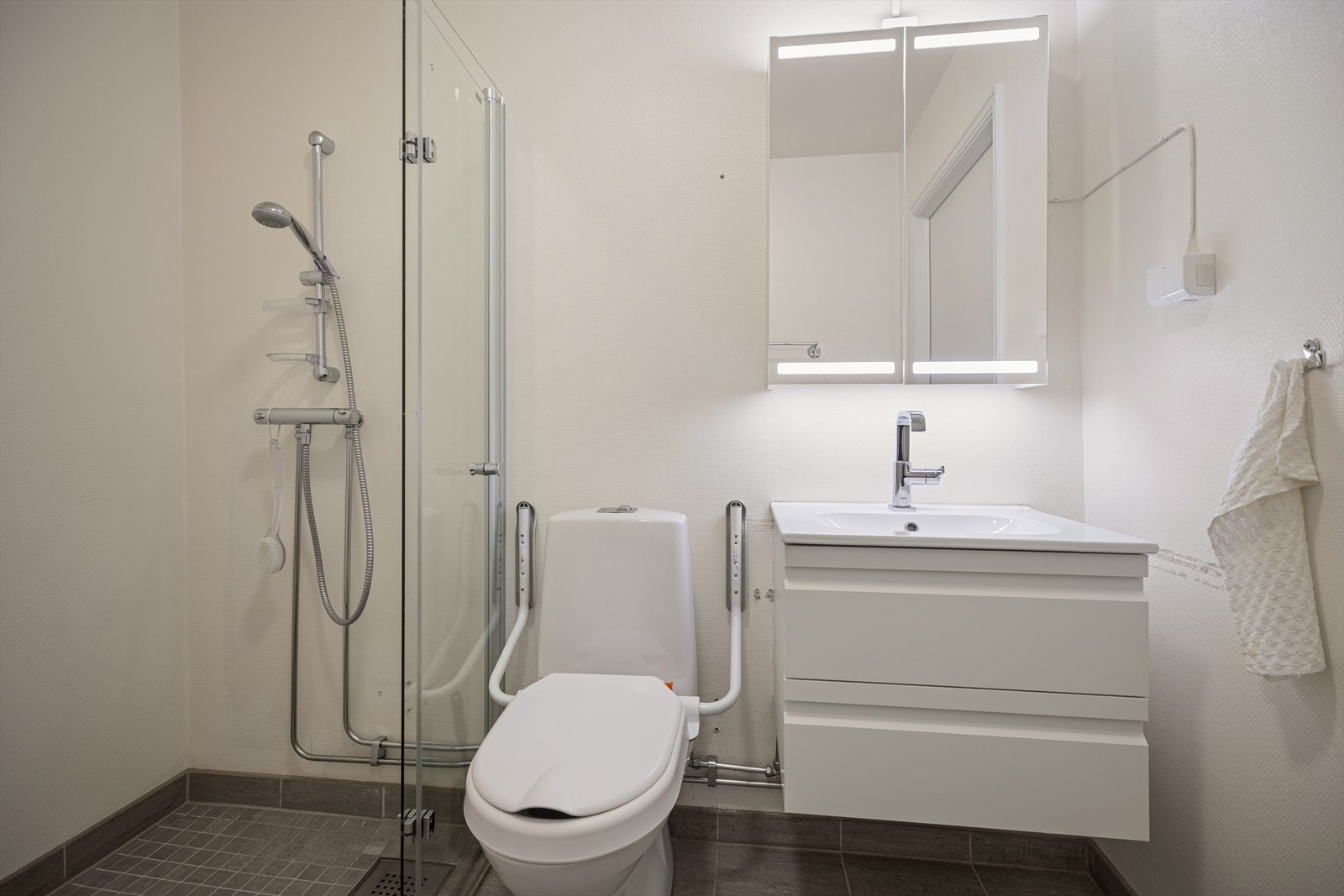 Badet er innredet med nedfelt servant, toalett og nedsenket dusjhjørne med dør i herdet glass. Galleribilde