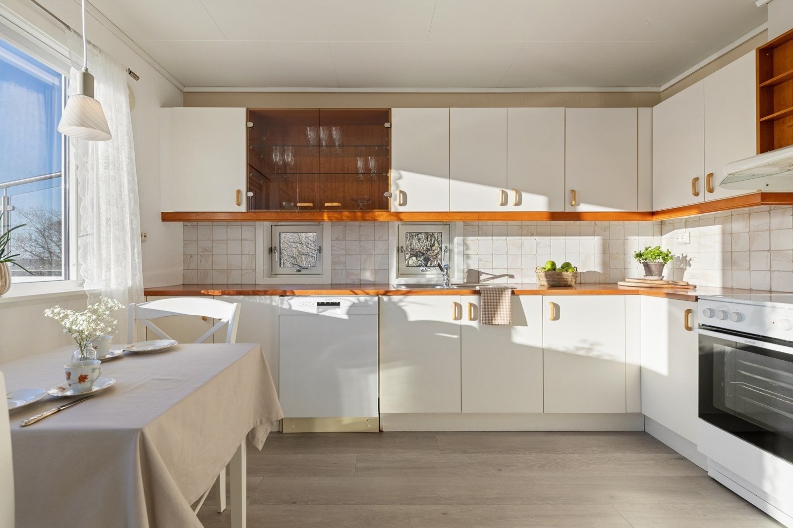 Pent kjøkken fra byggeår, innredning med slette fronter og benkeplate i laminat utførelse. Fliser som backsplash. Kjøkkenventilator med avtrekk ut. Galleribilde