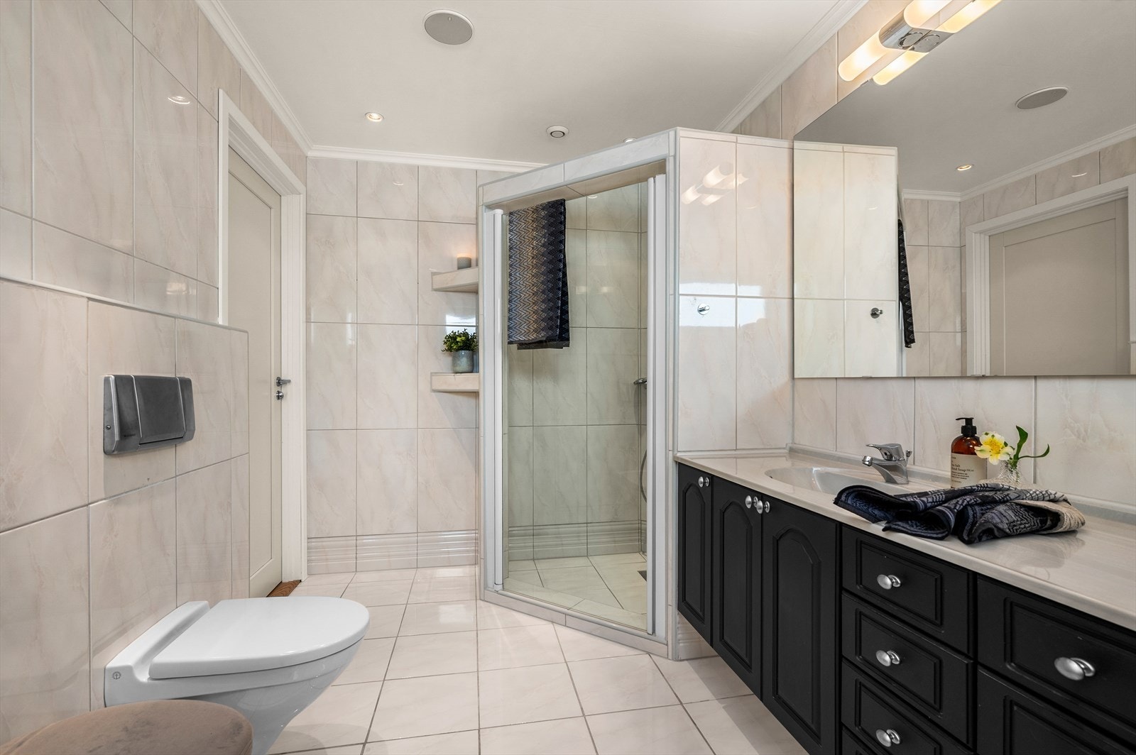 Stor servant med underskap, dushjørne og vegghengt WC på badet. Flott flislagt på både gulv og vegger Galleribilde