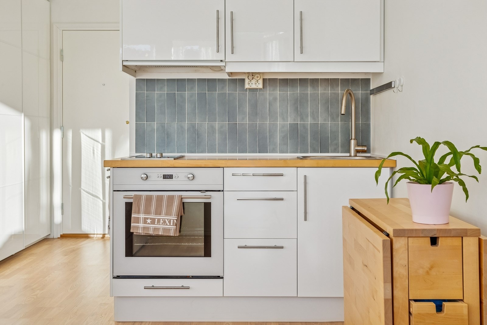 Kjøkkeninnredning med slette fronter, heltre benkeplate og integrert stekeovn med induksjonstopp. Galleribilde