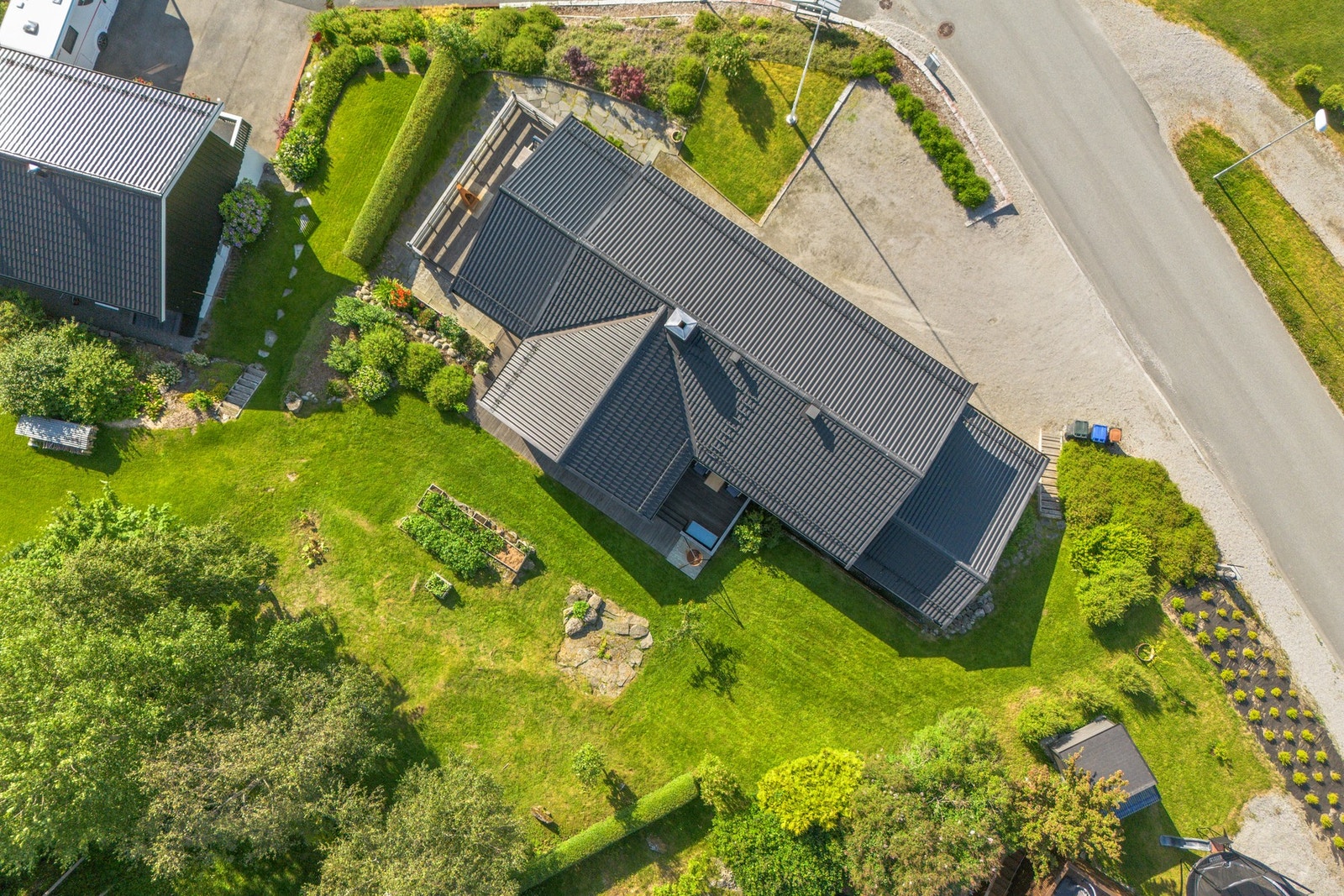 Svært pent opparbeidet tomt med busker, bed, mur, steinlagt terrasse, m.m. Galleribilde
