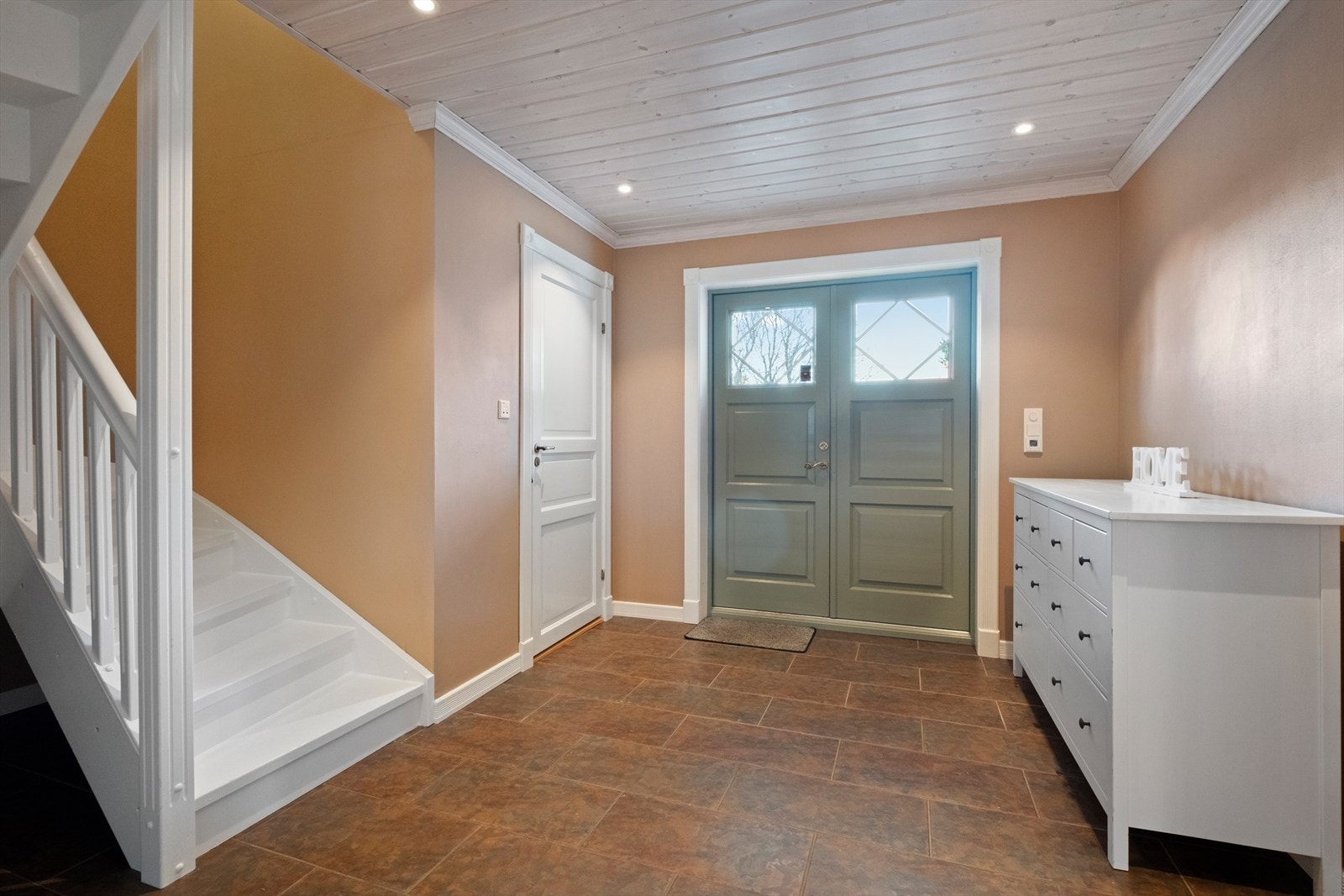 Romslig flislagt hall med varmekabler og dør til garderobe. Galleribilde