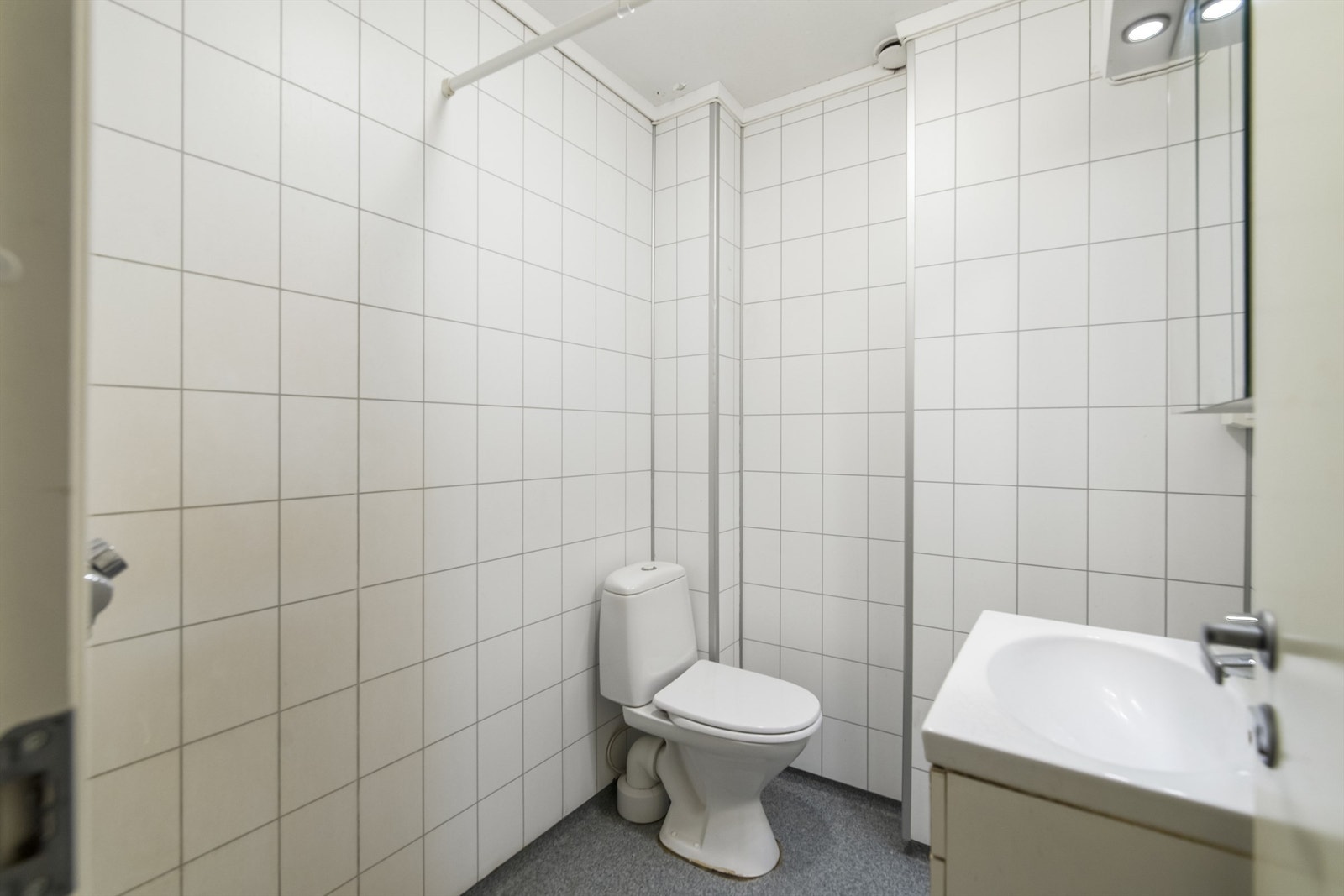 Lyst bad med dusjnisje, toalett og servant i innredning med overspeil Galleribilde