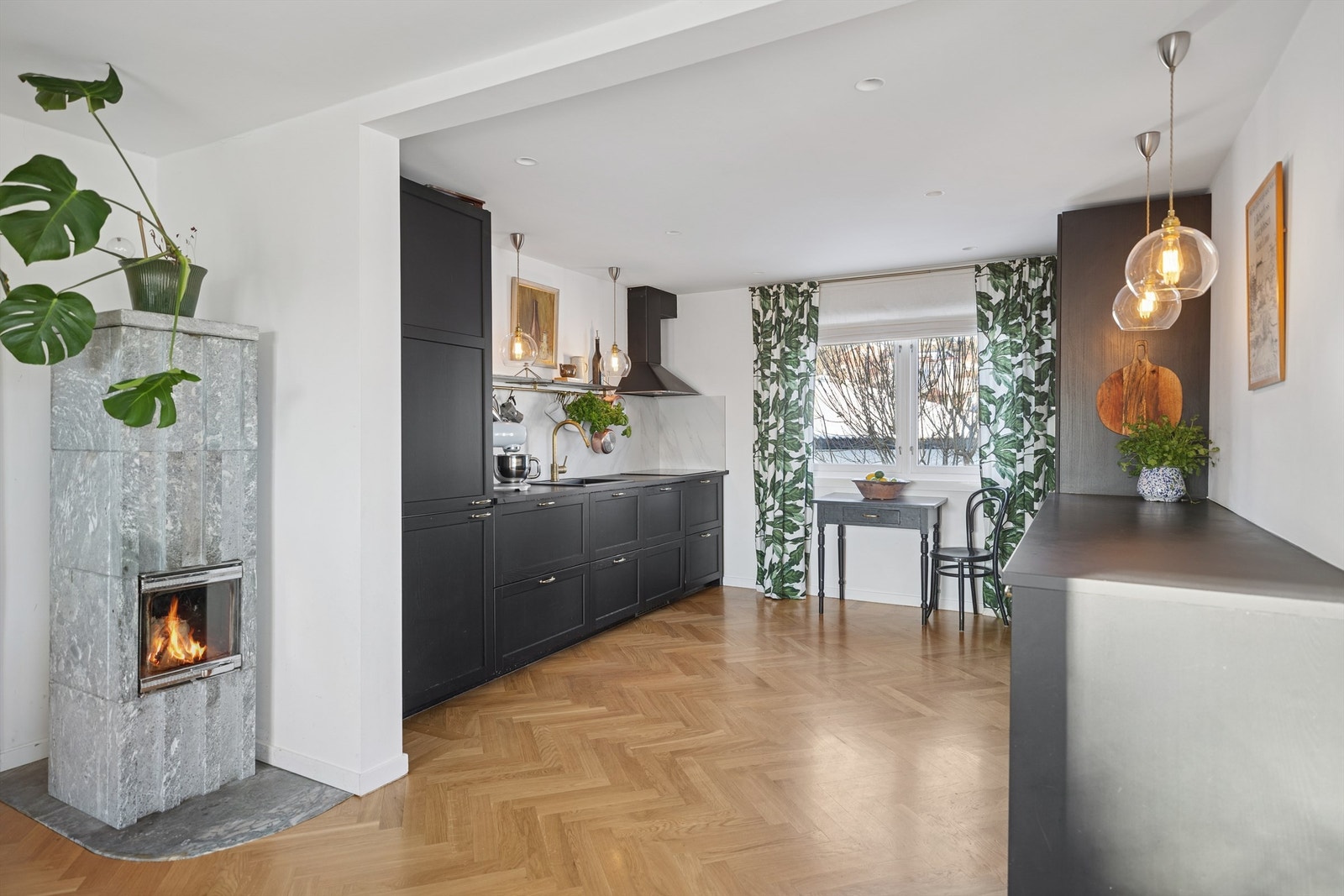 Åpent og sosialt kjøkken mot stuen, samt en vakker klebersteinsovn som både fungerer som romdeler og estetisk blikkfang. Galleribilde