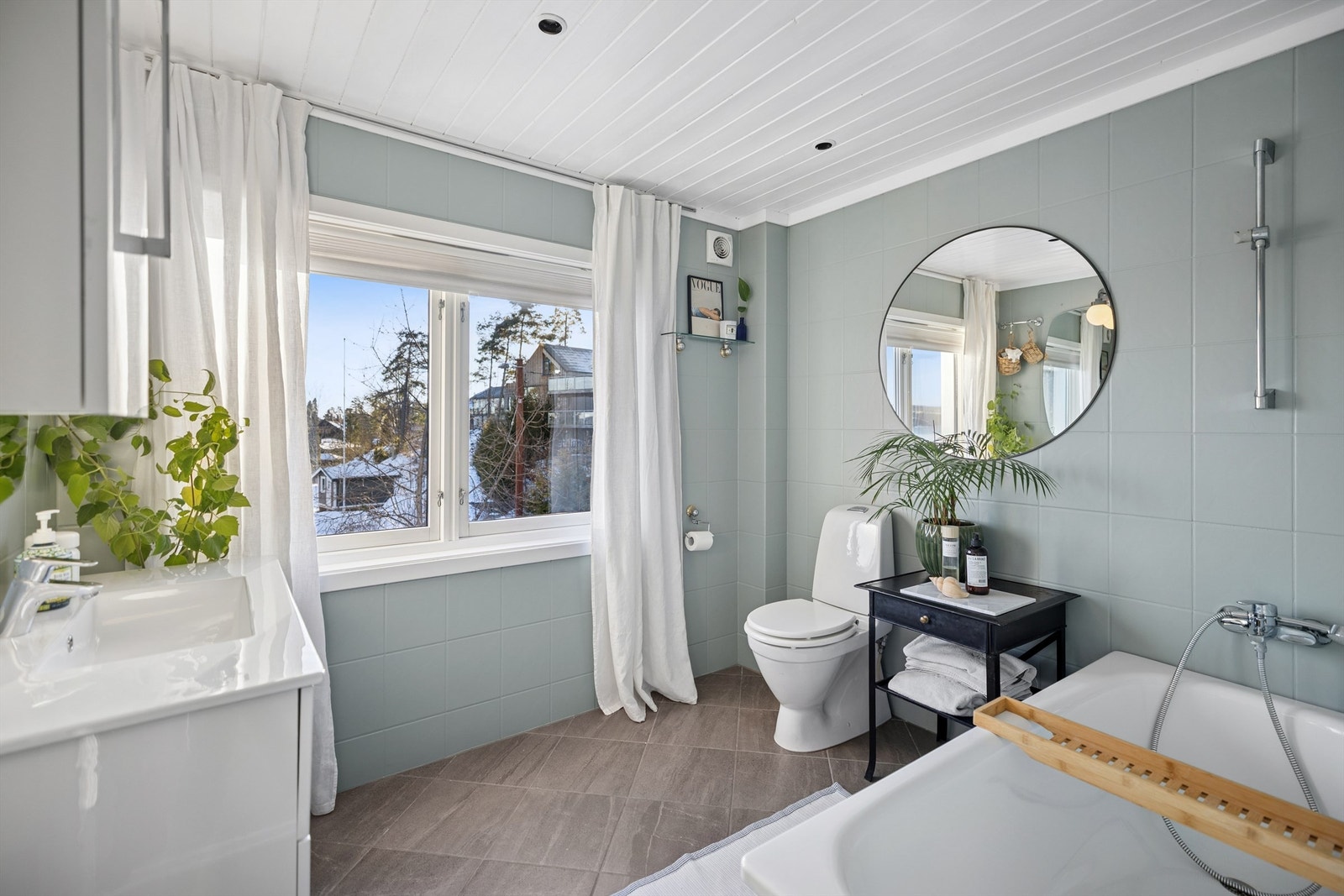 Frittstående badekar med veggmontert dusjarmatur og gulvstående toalett. Galleribilde