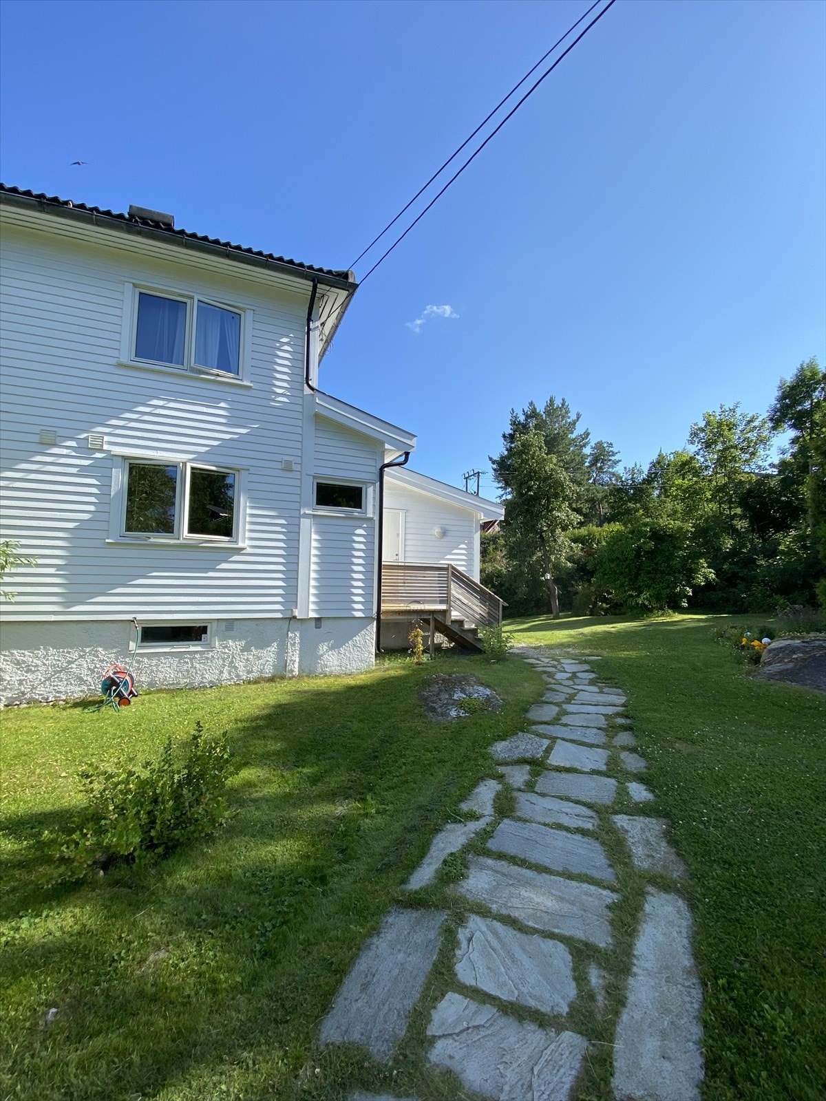 Eiendommen er et hageparadis på sommeren som både er praktisk og idyllisk, og du finner en skiferbelagt adkomst til huset. (privat foto) Galleribilde