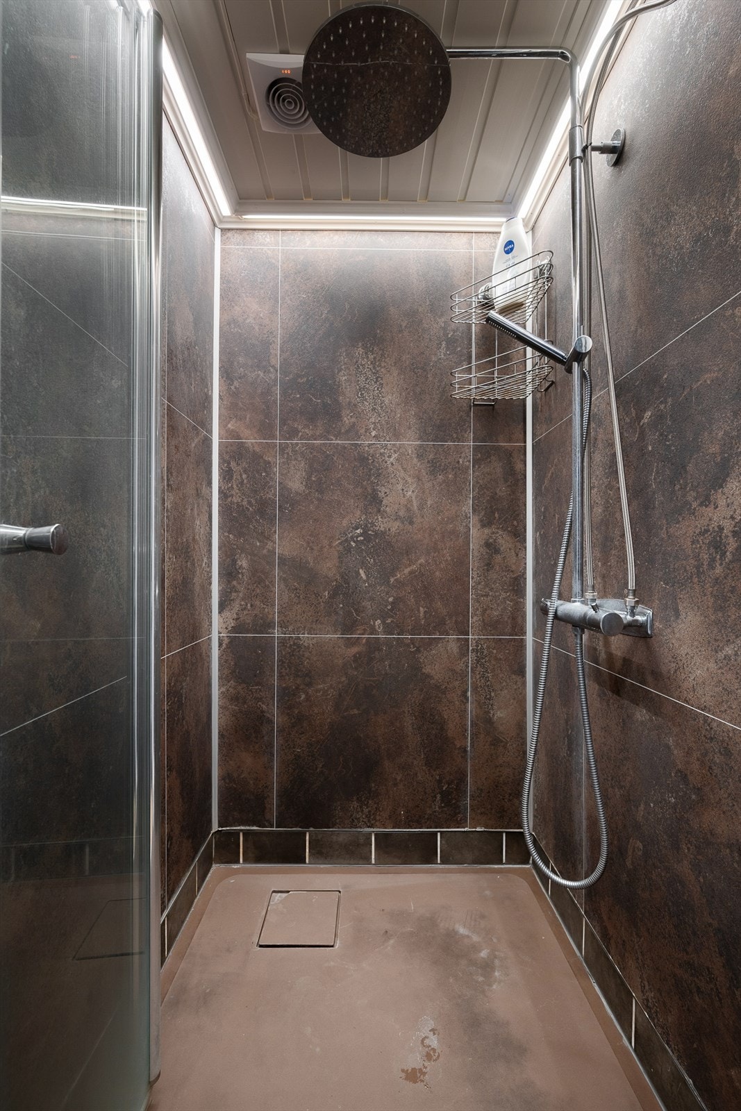 Eget dusjrom med flislagte overflater og regnfallsdusj. Galleribilde