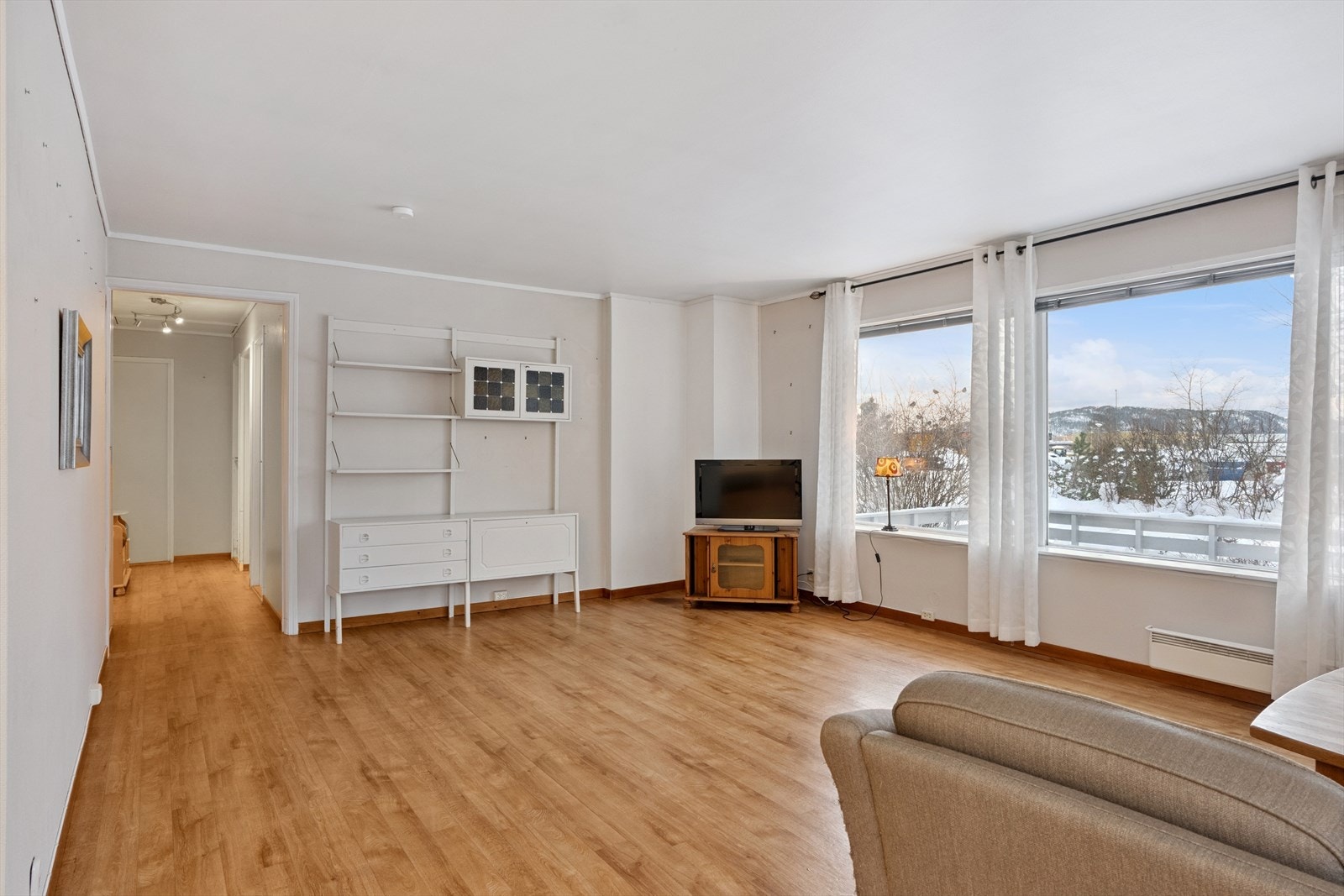 Åpen stue med store vindusflater mot veranda/hage. Galleribilde