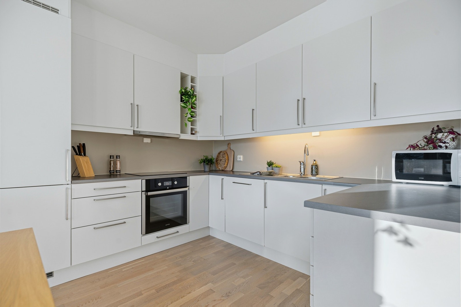 Kjøkkenet har hvite, glatte fronter, takoppforede veggskap og benkeplate i mørk laminat. Samtlige hvitevarer medfølger. Galleribilde