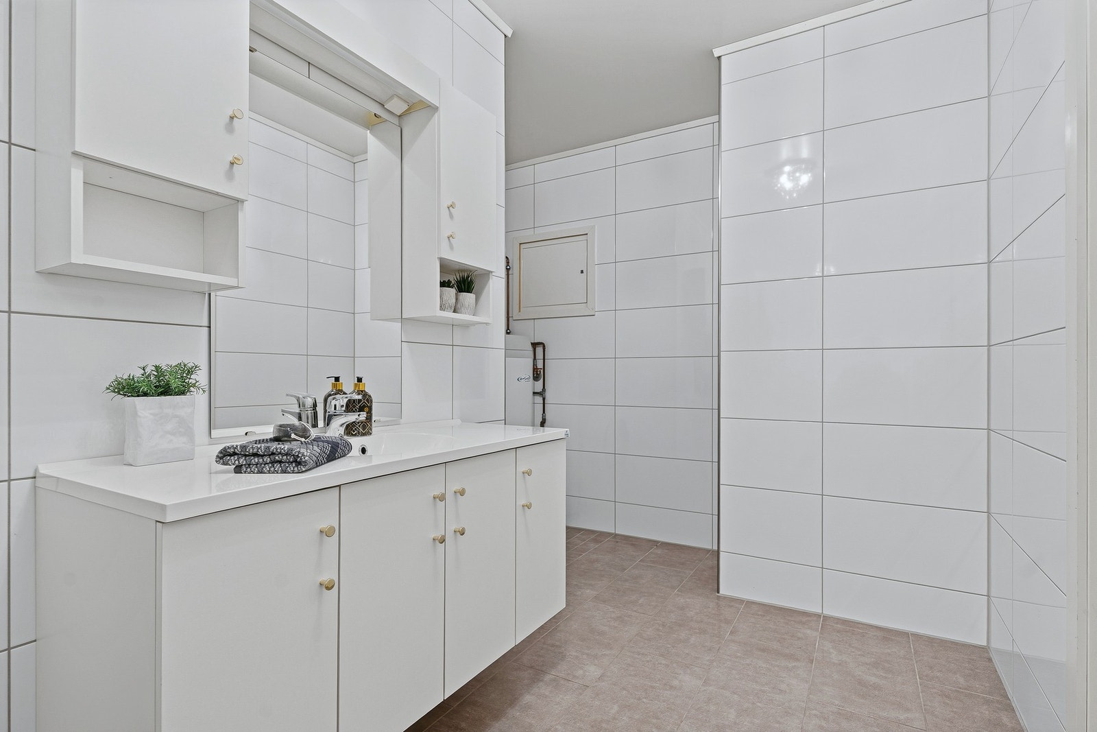 Badet har opplegg for vaskemaskin og er pent innredet med toalett, hvitt servantmøbel og speilskap. Galleribilde