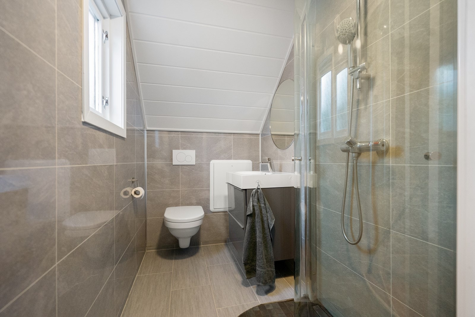 Flislagt bad i 2. etasje med praktisk dusjløsning, servant og vegghengt toalett Galleribilde