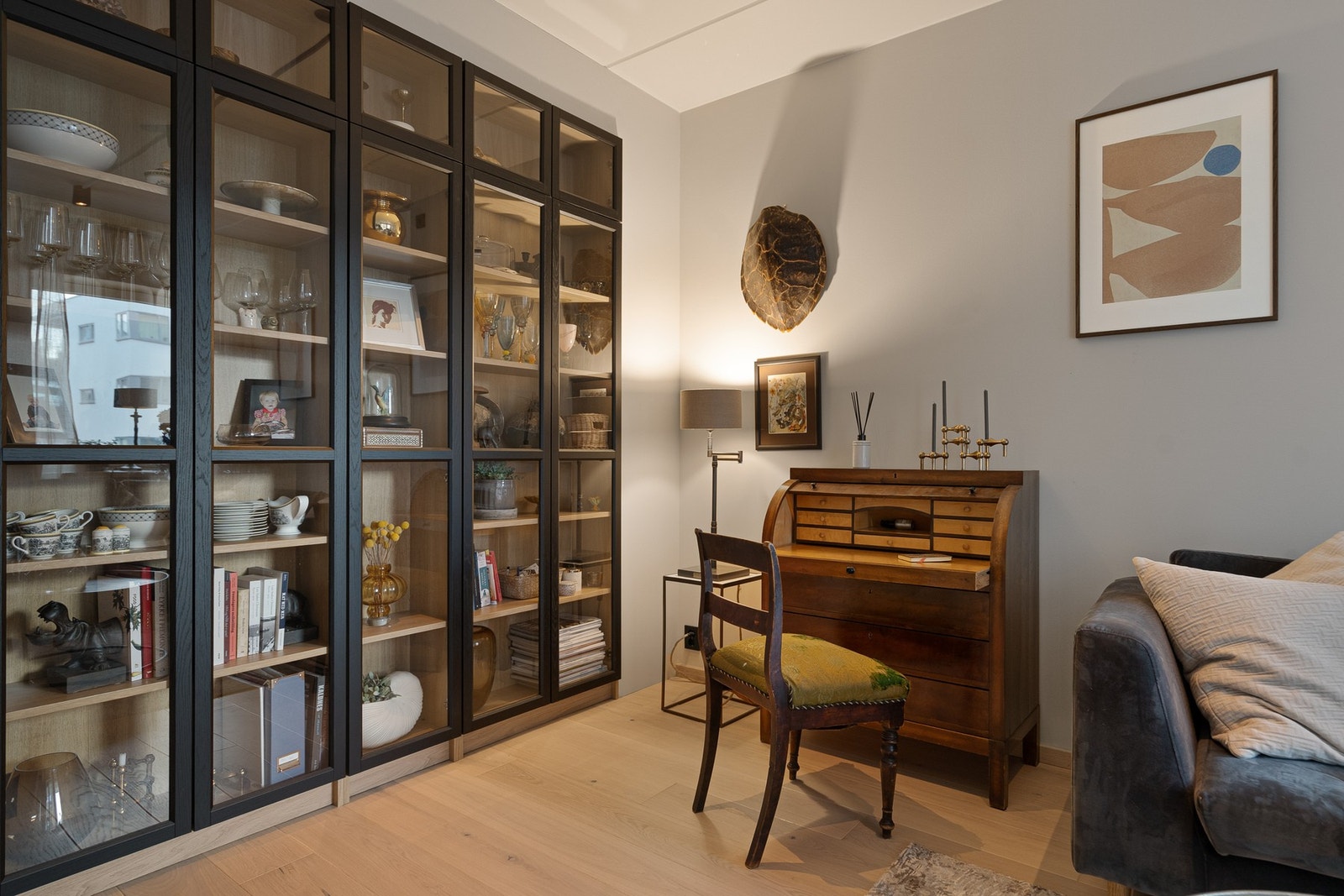 Et naturlig blikkfang i rommet er den plassbygde hyllen med glassfronter, som gir både praktisk oppbevaring og en fin ramme rundt rommet. Den tilfører karakter uten å ta opp gulvplass, og passer godt inn i det helhetlige uttrykket. Galleribilde