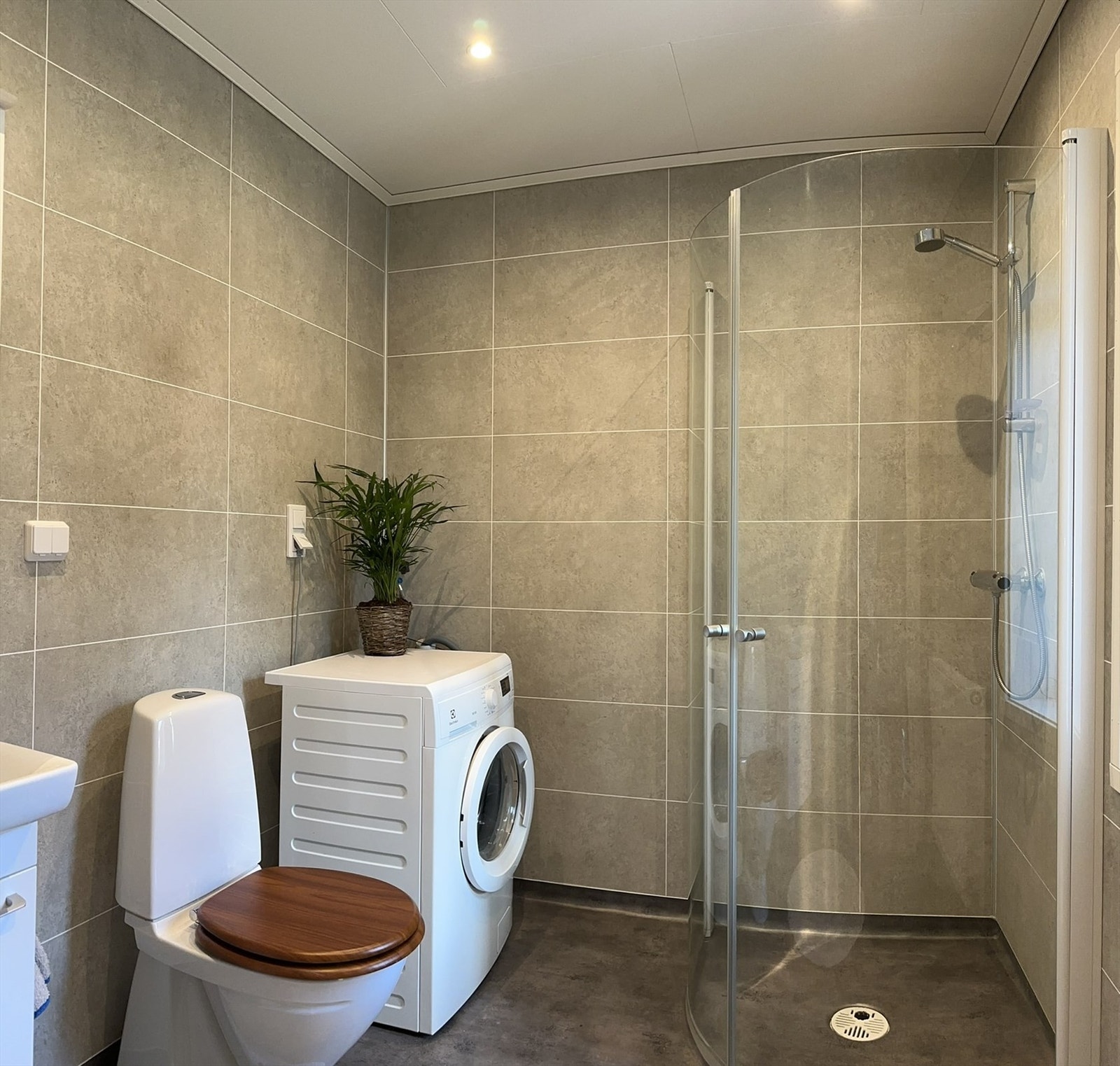 Baderom med gulvbelegg og baderomsplater på veggene. Det er elektriske varmekabler i gulvet. Galleribilde