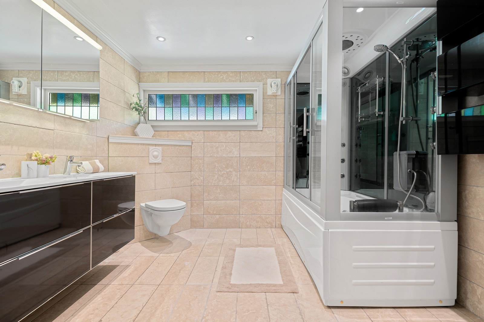 Innredet med veggmontert toalett, heldekkende dobbel servant i baderomsinnredning og stort dusjkabinett Galleribilde