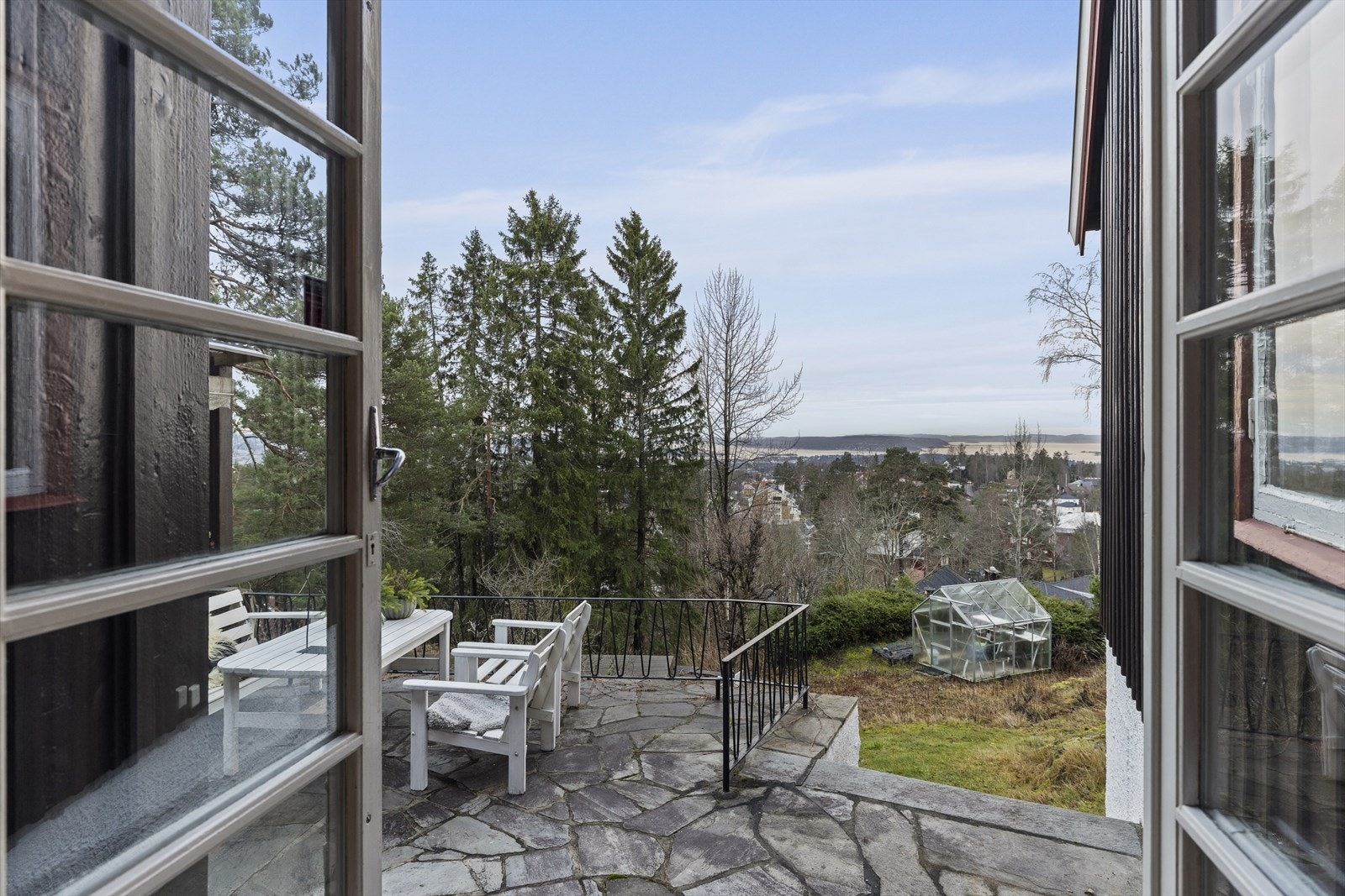 Stor terrasse belagt med bruddskifer, trapp ned til hagen. Galleribilde