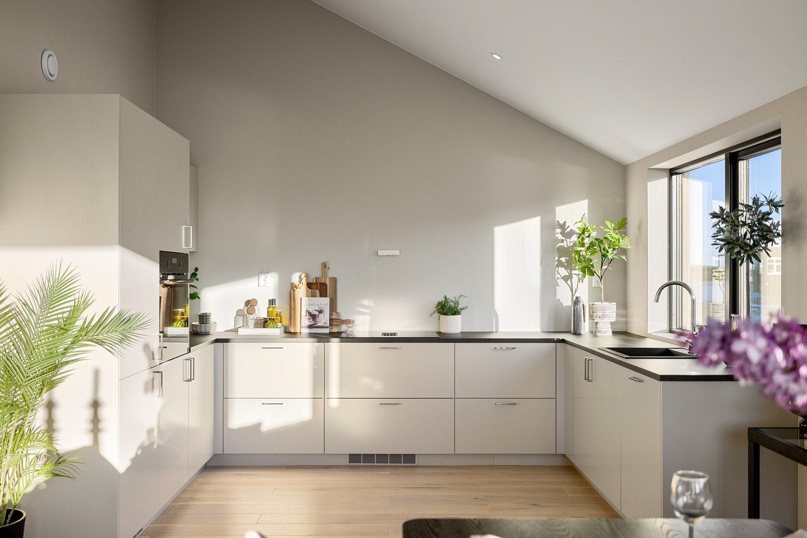 Moderne innredning med slette, lyse fronter og mørk, slitesterk benkeplate. Galleribilde