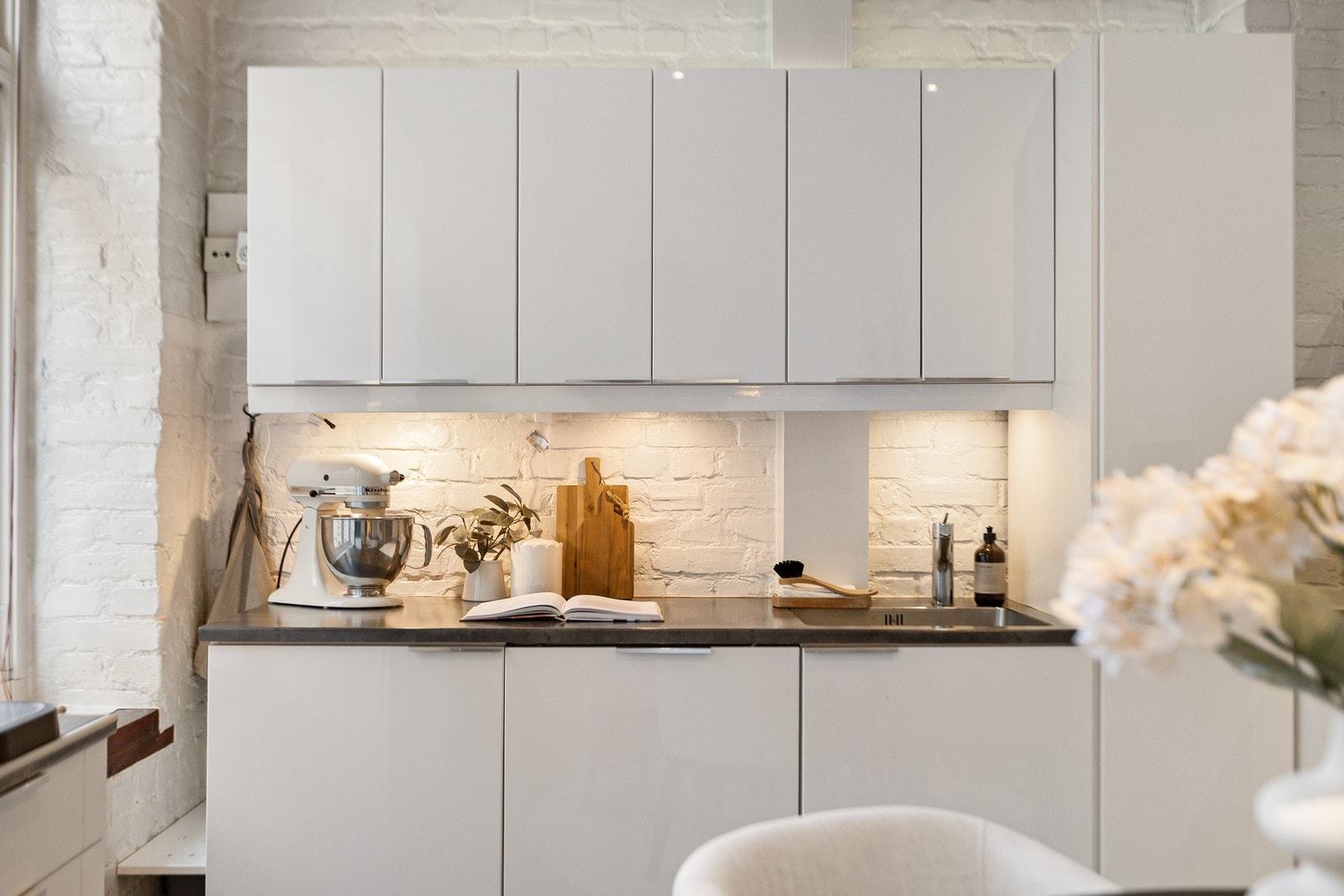 Innredningen fremstår moderne med hvite, høyglans fronter og benkeplate i laminat. Galleribilde