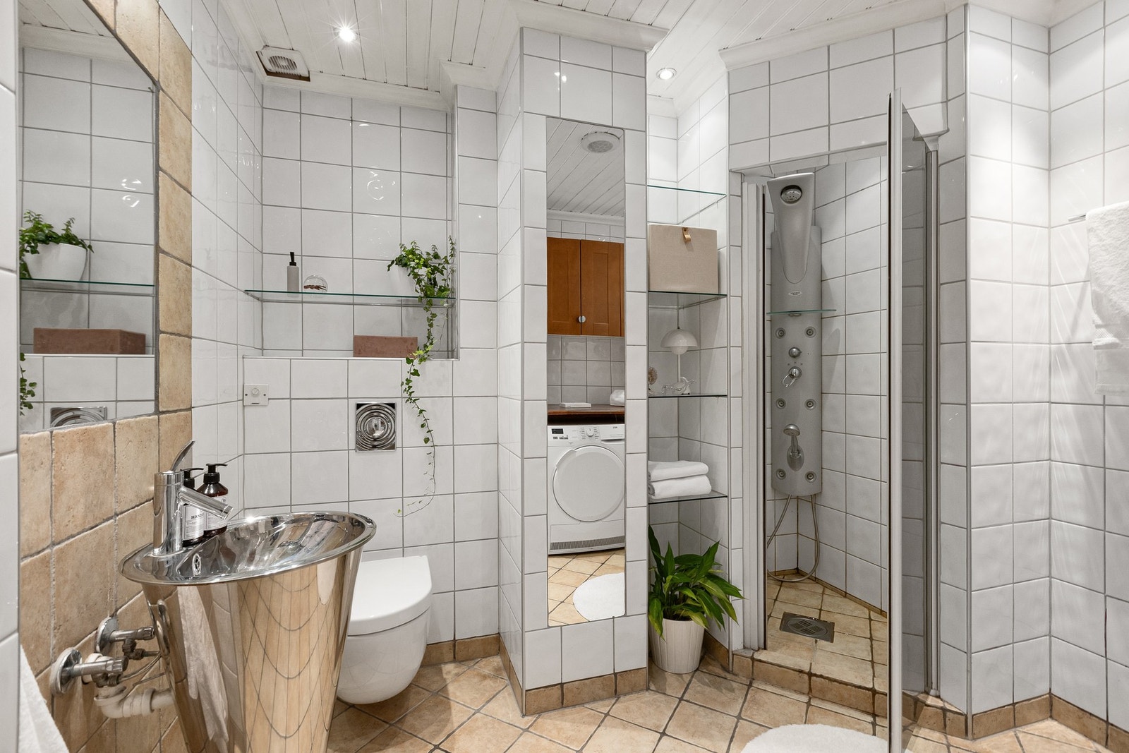 Leiligheten har et eldre baderom. Rommet fremstår som funksjonelt med fliser på alle flater og varmekabler. Galleribilde