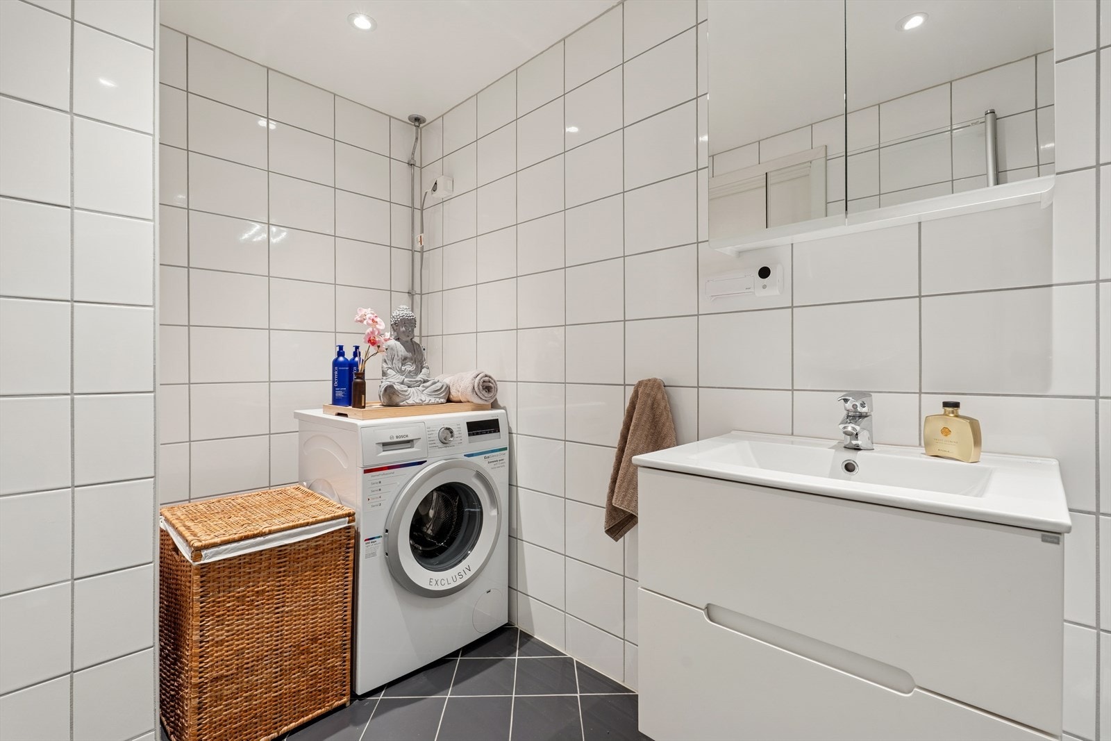 Badet er utstyrt med dusjhjørne, opplegg for vaskemaskin og en moderne baderomsinnredning. Det er behagelige varmekabler i gulv. Galleribilde