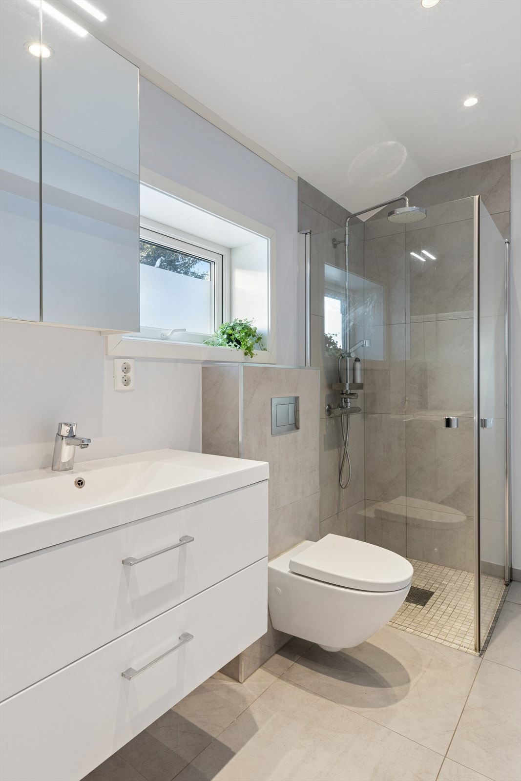 Servant med skuffer, speil overskap. Vegghengt toalett og dusjdører i herdet glass. Galleribilde