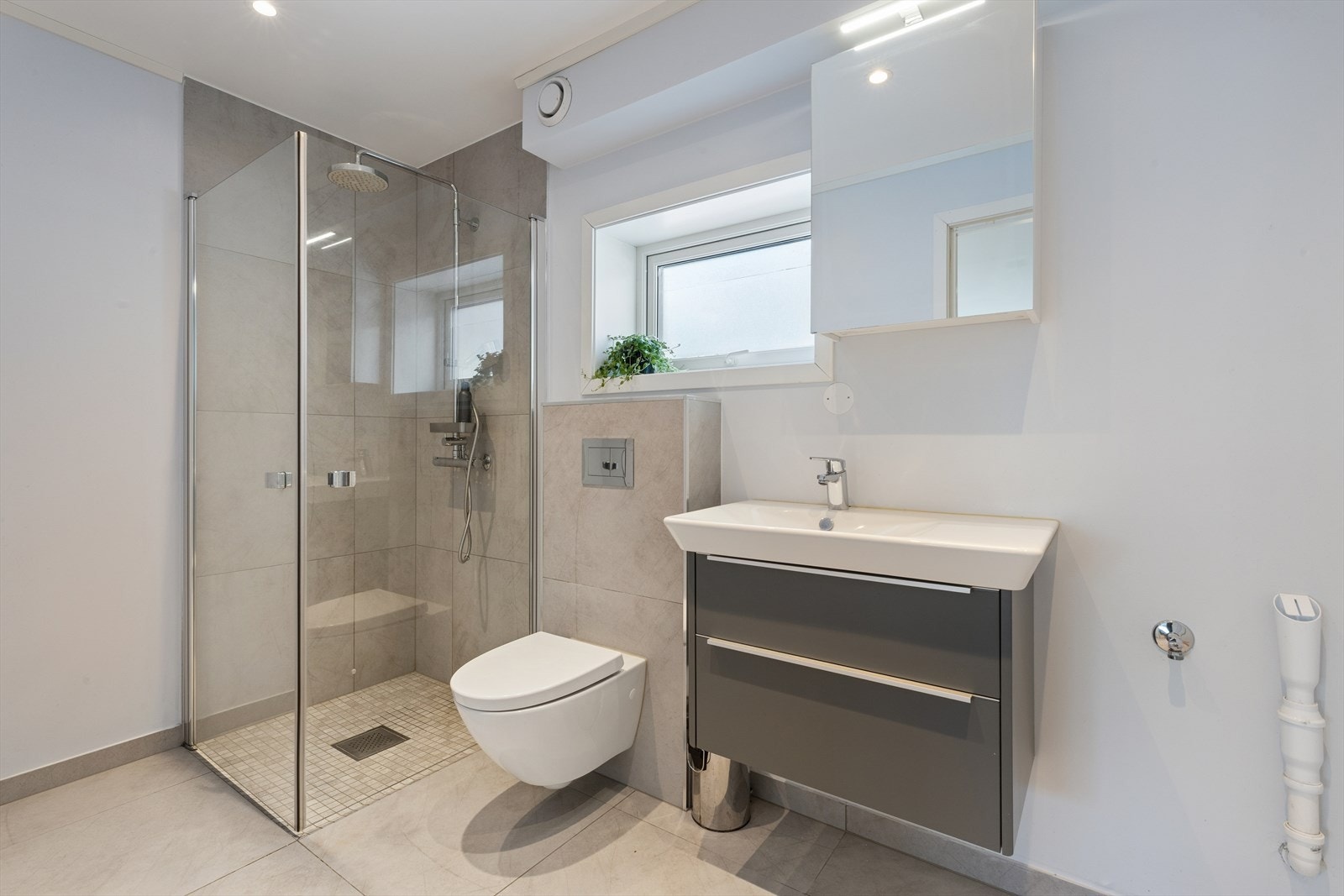 Flislagt bad i 1. etasje med varmekabler, vegghengt klosett og innfellbare dusjdører i herdet glass gir et moderne inntrykk. Galleribilde