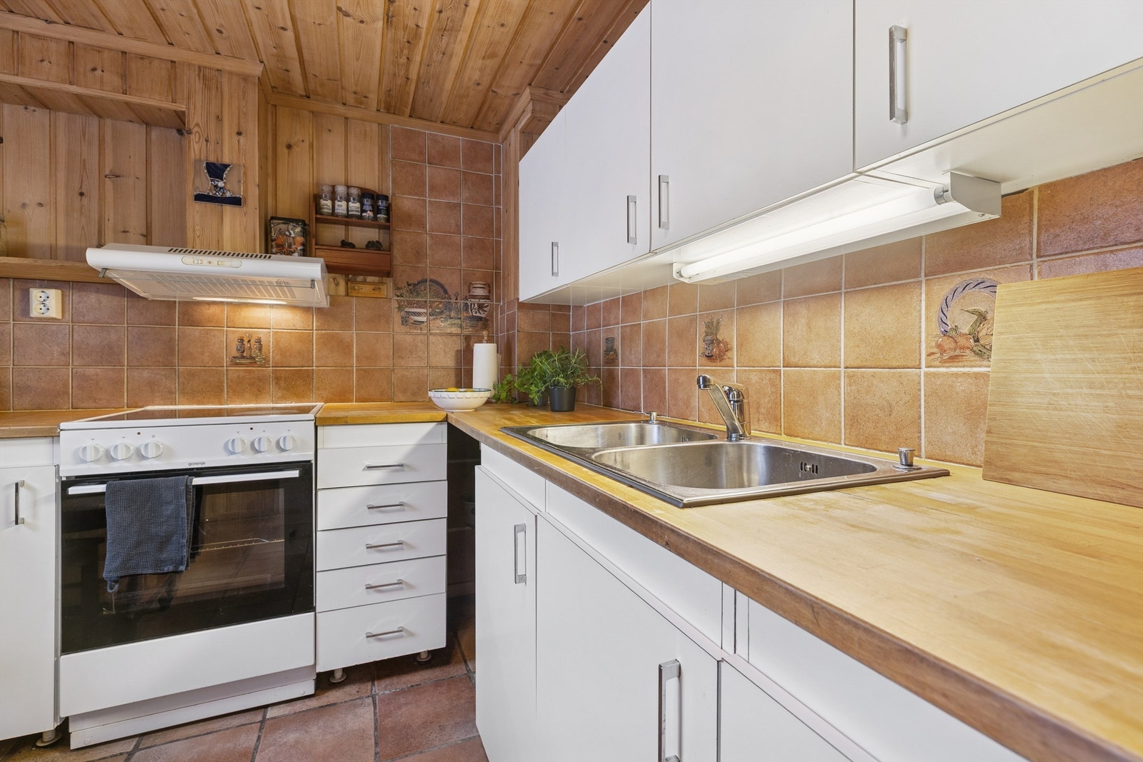 Det er flislagte vegger over kjøkkenbenkene, og god belysning under overskapene. Galleribilde