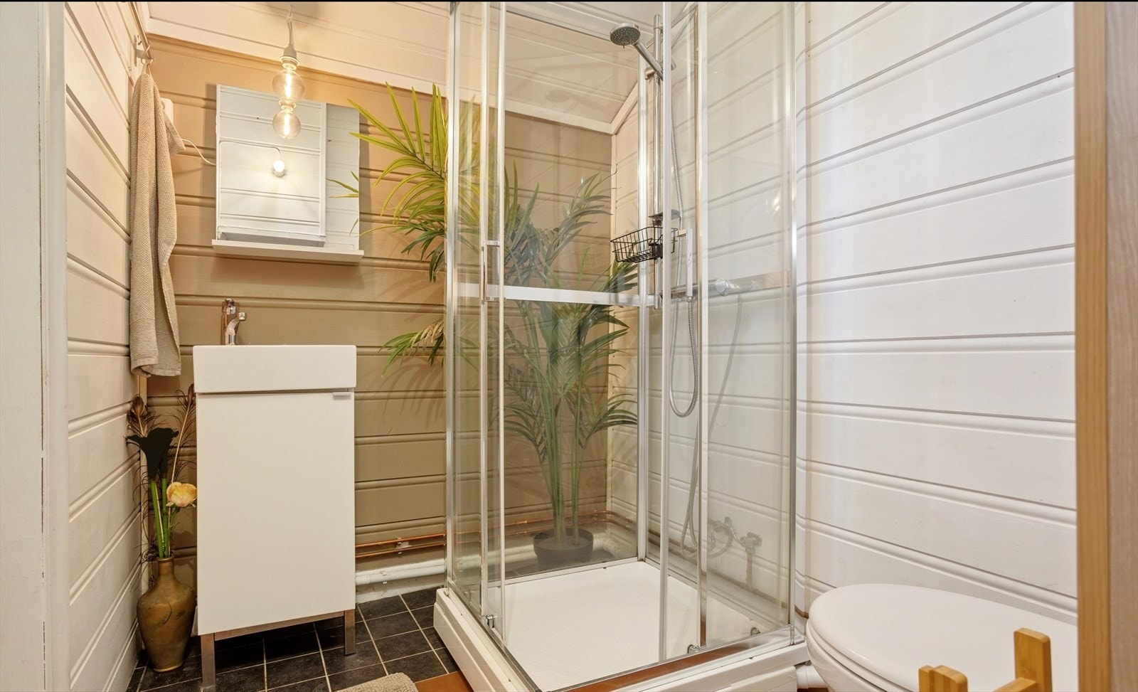 Bad nr. 2 har keramiske fliser på gulv, malt panel på vegger og i himling, og er utstyrt med servant, vegghengt wc og dusjkabinett. Galleribilde