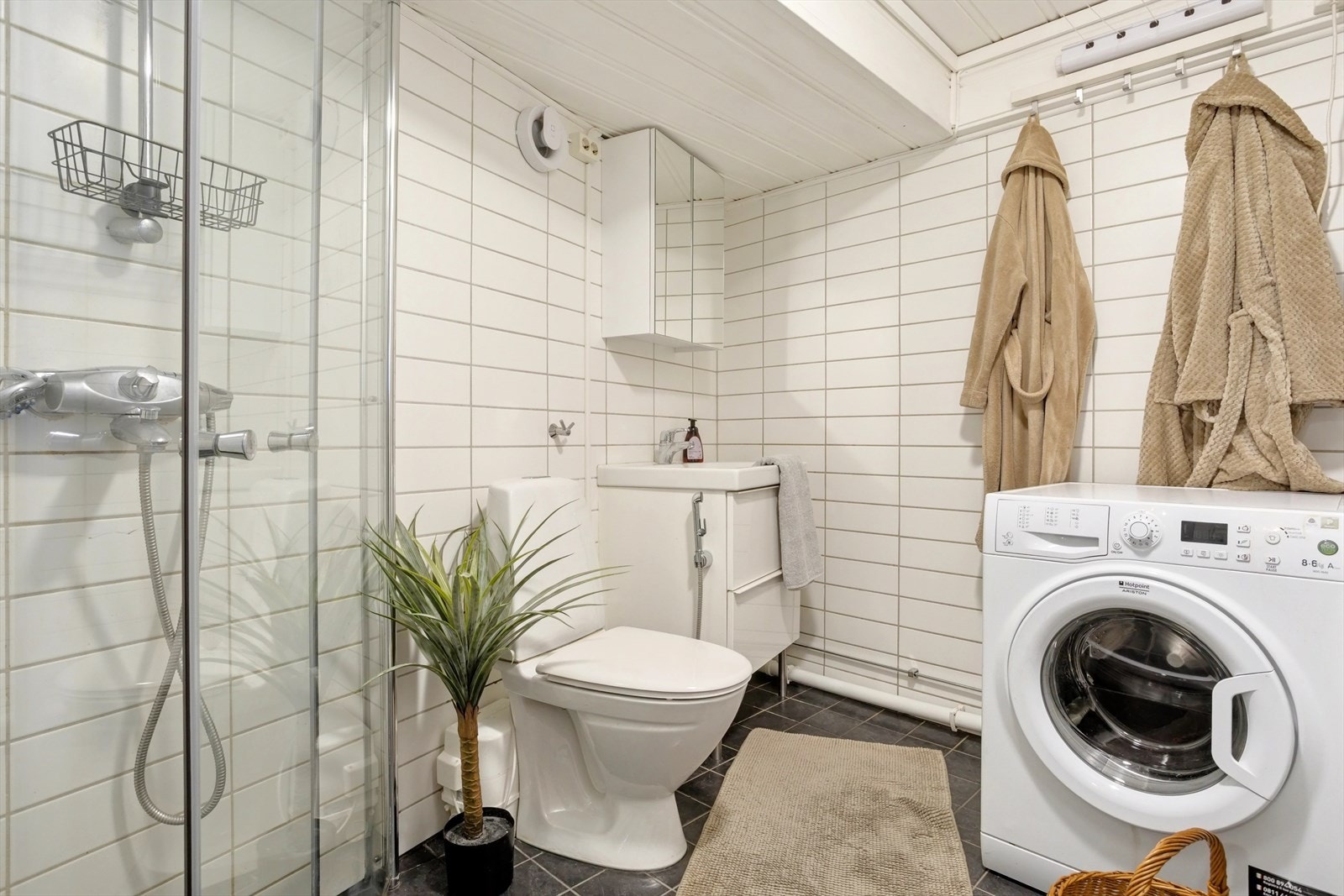 Badet har servant med møblement og speil, toalett, dusjgarnityr, innfellbart dusjhjørne og opplegg for vaskemaskin. Elektrisk avtrekksventil i vegg gir god ventilasjon. Galleribilde