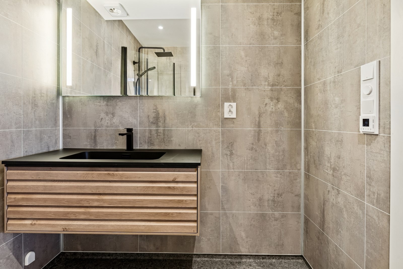 Badet har heldekkende servant i stilfull innredning og dusjhjørne med tropedusj. Galleribilde