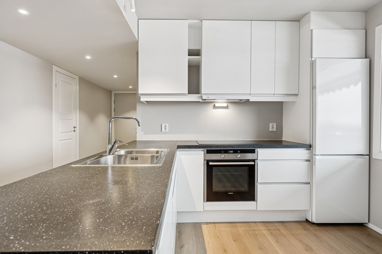 Praktisk kjøkkeninnredning med glatte fronter, takhøye overskap og laminat benkeplate. Galleribilde