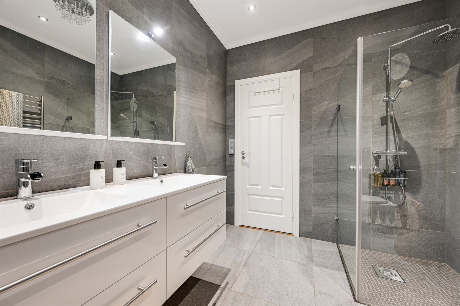 Badet er innredet med 2 nedfelte servanter, veggmontert toalett og dusjvegger/hjørne. Galleribilde