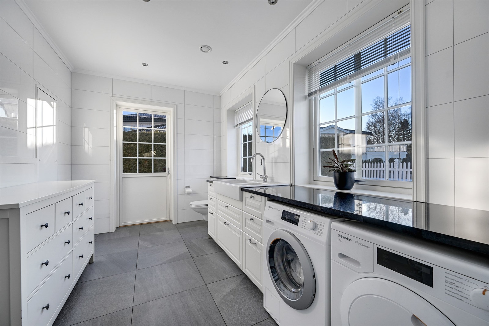 Romslig vaskerom/wc med plassbygget benkeplate for praktisk oppbevaring og bruk. Direkte adkomst ut terrassedør. Rommet er næringsareal. Galleribilde