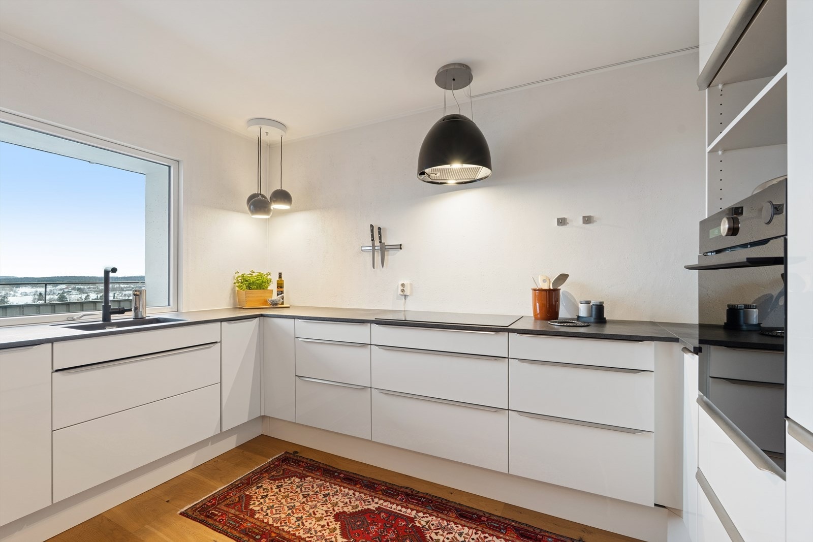 Slik skal det gjøres! Fyll opp veggene med innredning under benk slik at lyset og romfølelsen ivaretas - høyskapene perfekt plassert på bakveggen - nisje for kaffemaskin, ekstra stekeovn e.l. Galleribilde