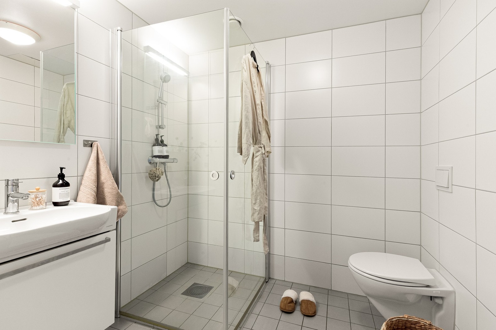 Baderom fra byggeår i en lys og tidsnøytral utførelse. Det er også en nisje for vaskesøyle t.h. i det man kommer inn. Galleribilde