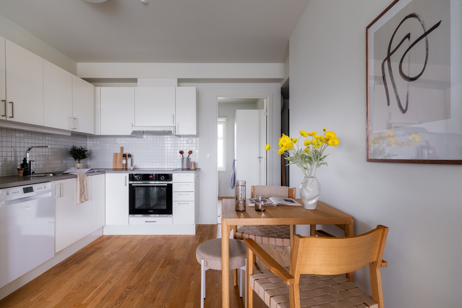 Lyst, pent kjøkkenhjørne med glatte fronter og laminat benkeplate med flisfelt på overside. Galleribilde