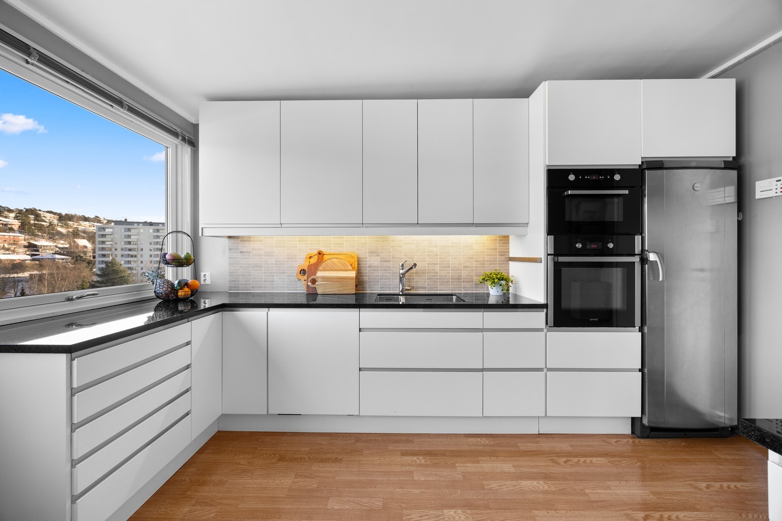 Innredningen fra Ikea har hvite, glatte fronter og sort benkeplate i stein med underlimt kum i stål. Det er installert automatisk lekkasjestopper på kjøkkenet. Galleribilde