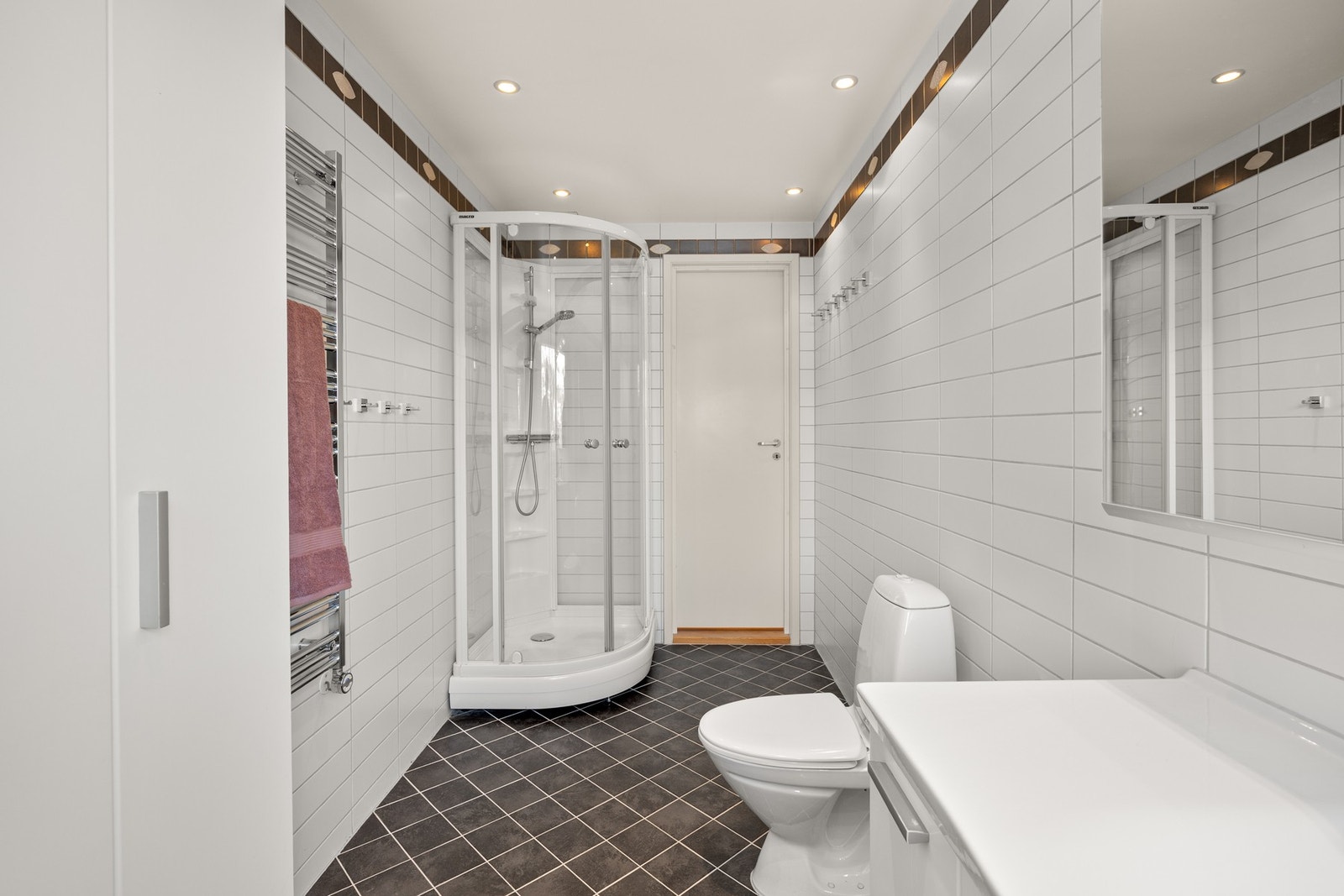 Innredningen består av en heldekkende servant og flere høyskap for lagring. Videre har badet et toalett, elektrisk håndkletørker, mekanisk avtrekk og et dusjkabinett. Galleribilde