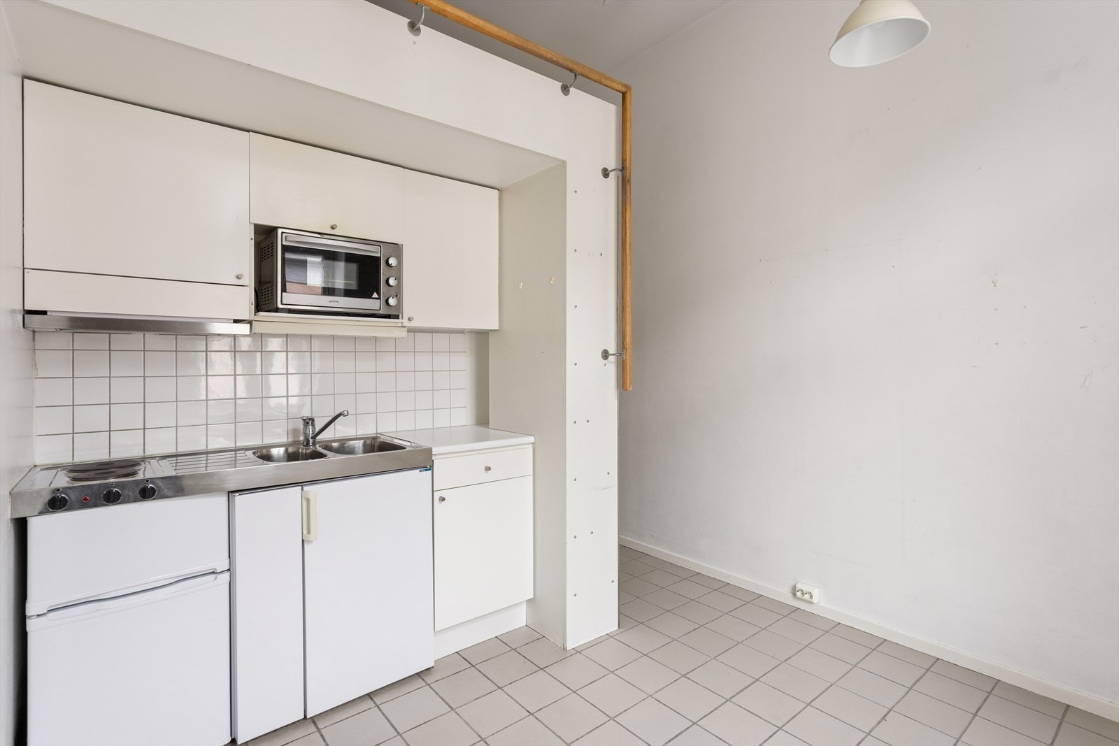 Praktisk hybelkjøkken med glatte, folierte fronter og benkeplate med rustfri stålkum. Galleribilde