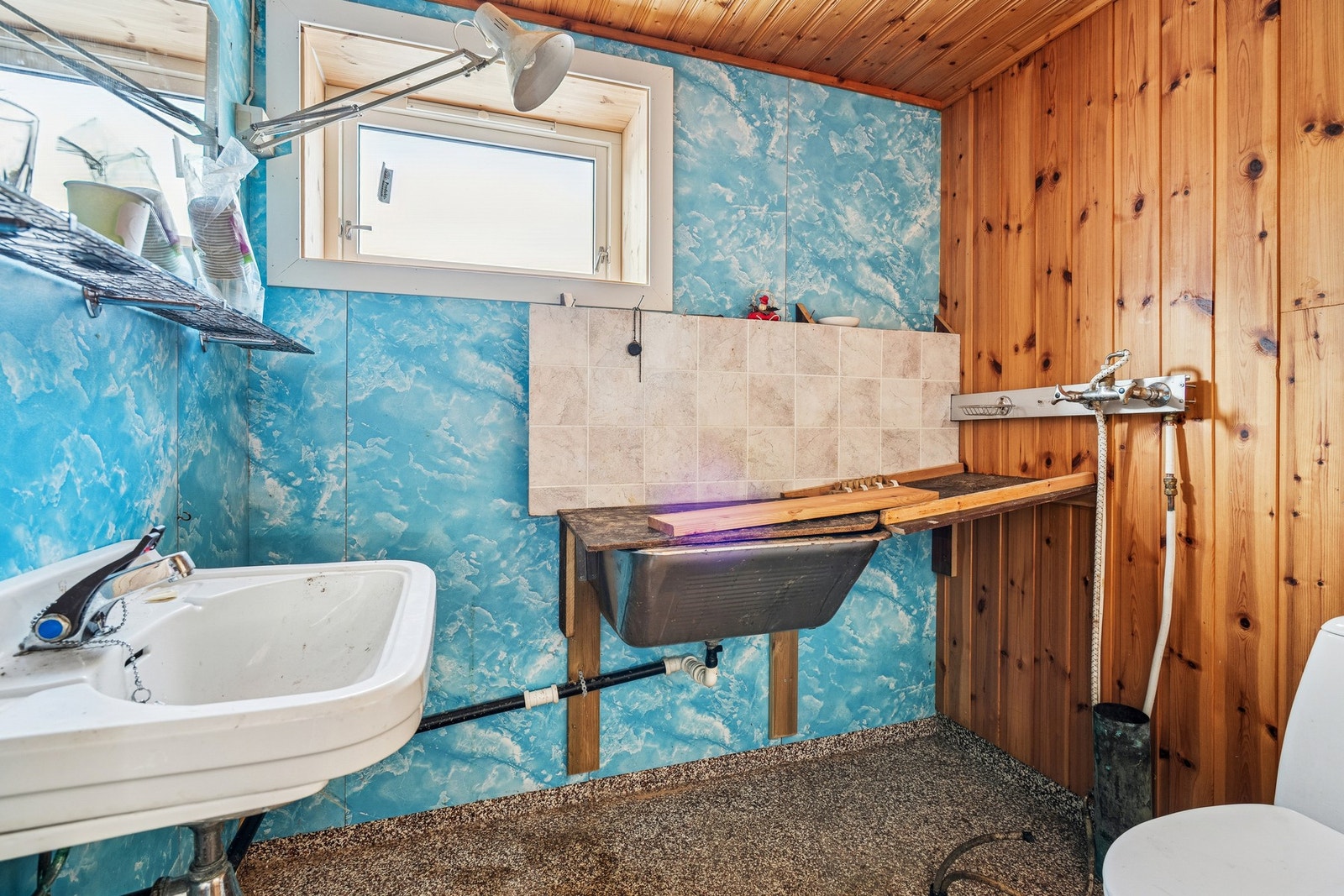 Toalettrommet er innredet med servant på vegg og frittstående toalett. Det er etablert vann på veggen og et skyllekar. Galleribilde