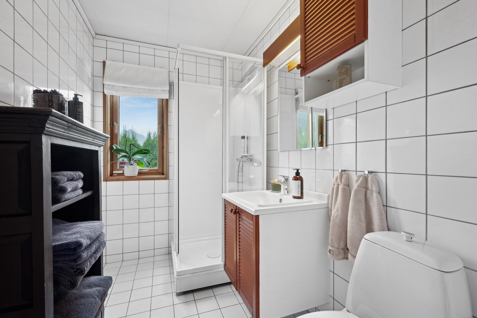 Badet i første etasje består av speil, servant med seksjon, overskap, toalett og dusjkabinett. Galleribilde