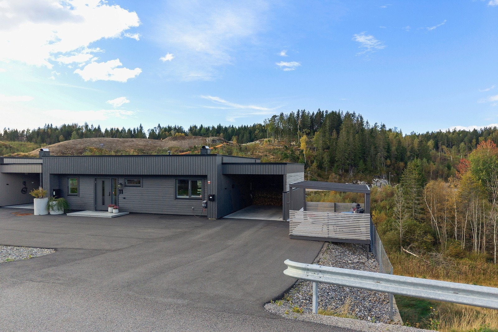 Foran huset er det asfaltert gårdsplass og innkjøring til carport med elbillader. Galleribilde