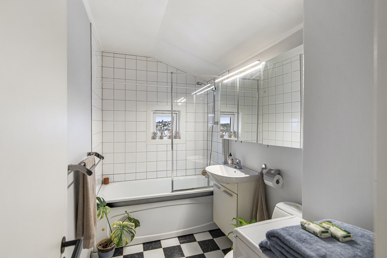 Pent og funksjonelt bad med flislagt gulv og badekar med dusjløsning. Galleribilde