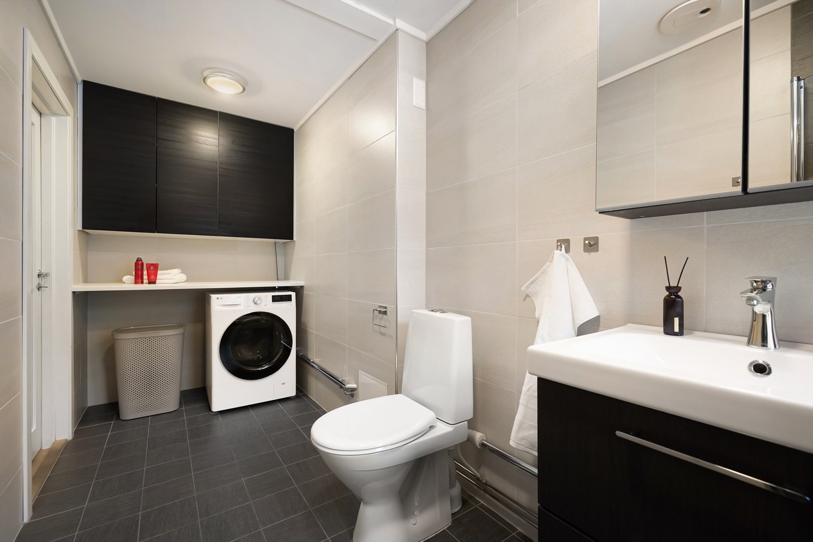 Badet er innredet med servant med underskap, speil med skap, dusjhjørne, WC, opplegg for vaskemaskin, samt praktisk benkeplate med overskap. Galleribilde