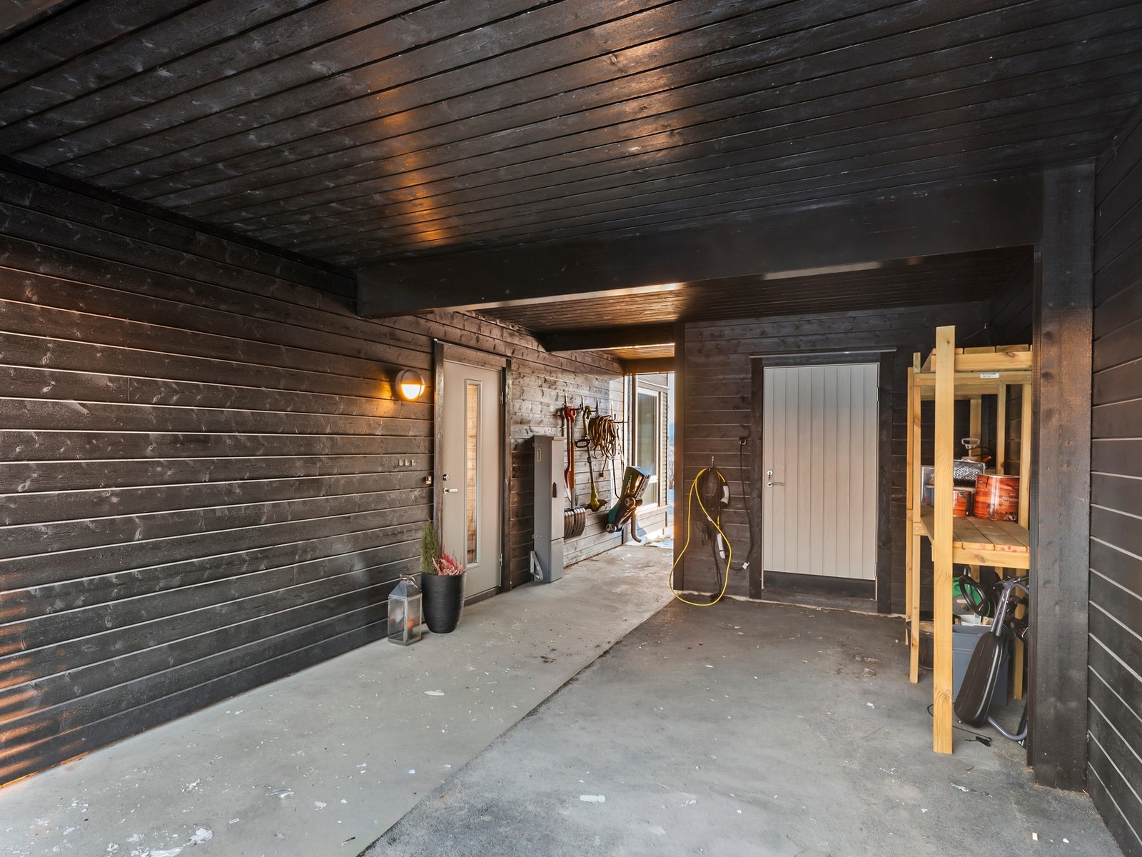 Parker bilen i romslig carport med uttak for elbil-lader. I bakkant av carporten er det en praktisk sportsbod. Galleribilde